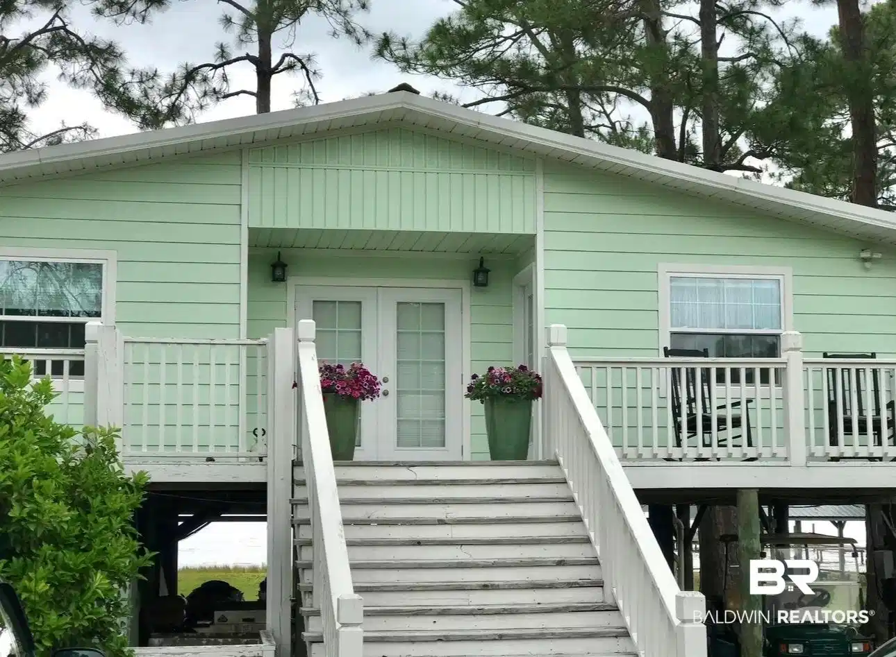 Image 1: Elevated residence featuring light green horizontal siding and white trim