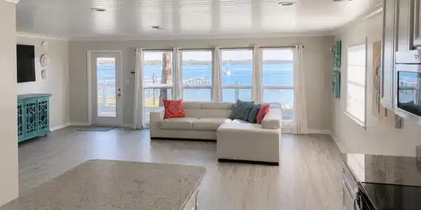 Image 2: Open-concept living area with water frontage, wide plank wood-finish flooring, recessed lighting, and a kitchen island with a stone countertop