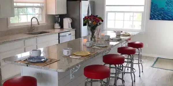 Image 3: Spacious kitchen featuring an extended island with granite-style countertops, white shaker cabinetry, stainless steel appliances, and wood-finish flooring