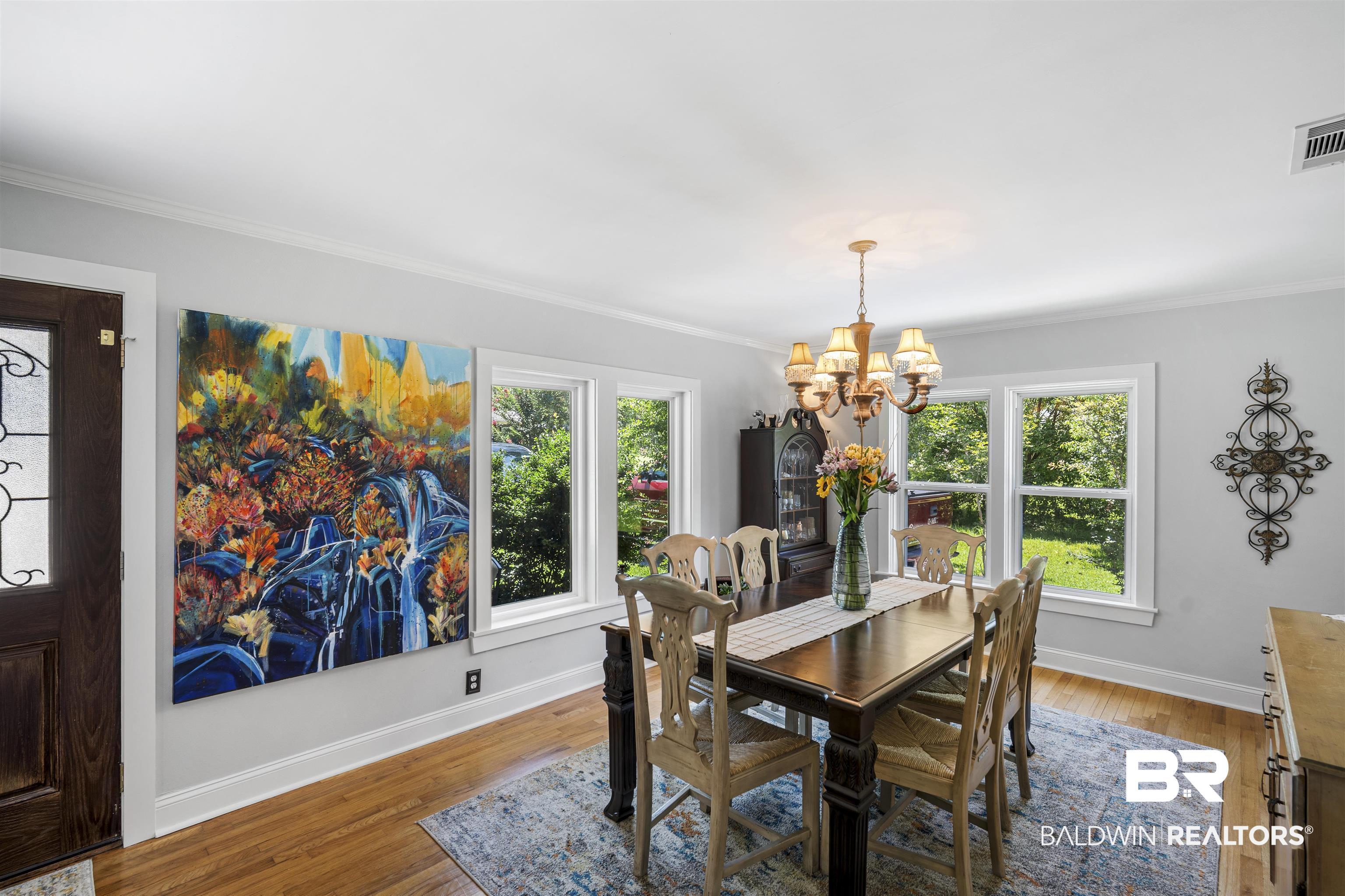 Image 4: Dining space featuring wood-finish flooring, white crown molding, and multiple windows