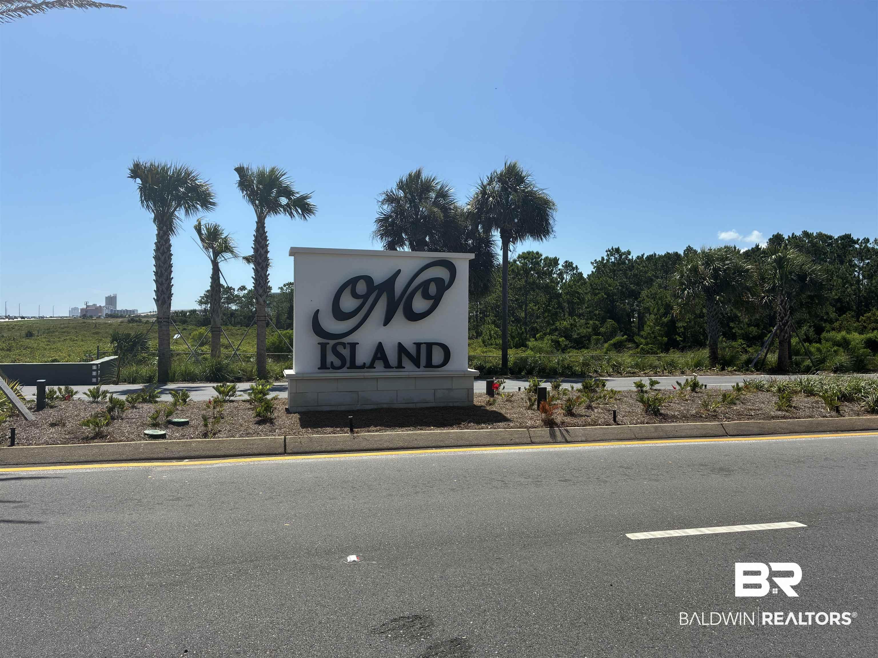 Image 3: Monument sign featuring raised lettering on a white rectangular facade, framed by mature palm trees and natural landscaping