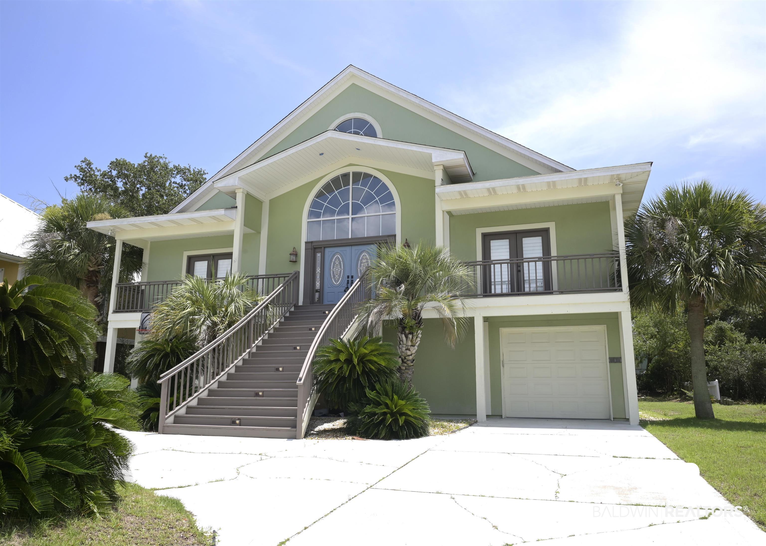 Image 4: Coastal-inspired residence featuring a prominent arched window, a covered entry with dual doors, and multiple balconies