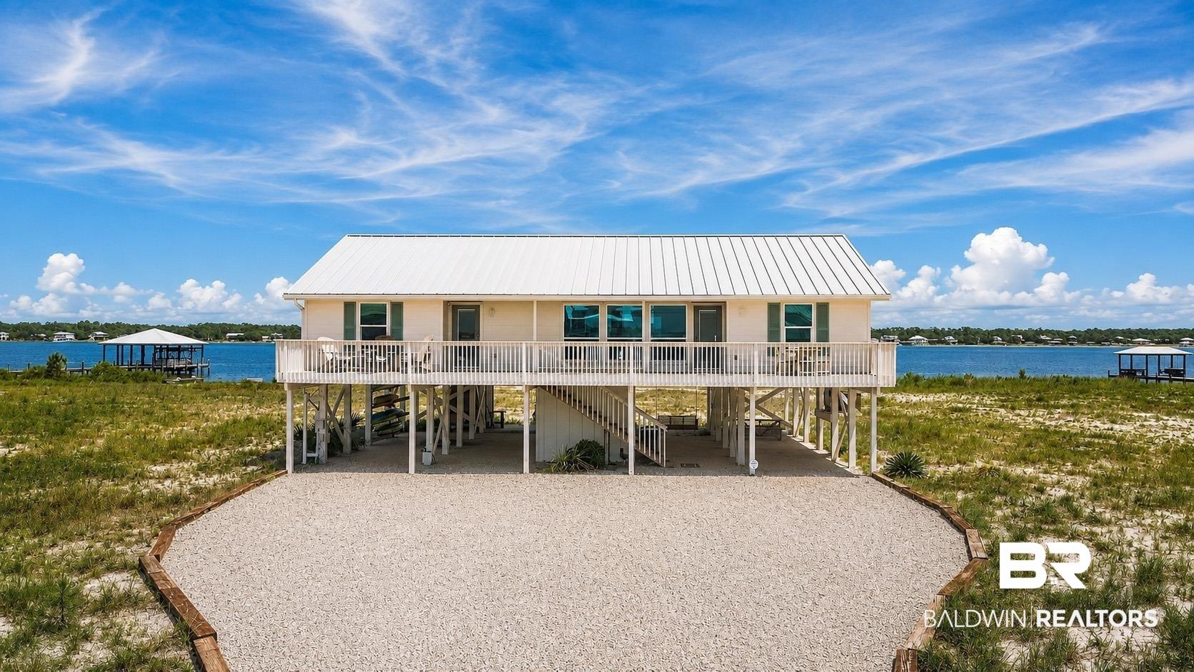 Image 4: Elevated coastal home featuring a covered front deck and white metal roof