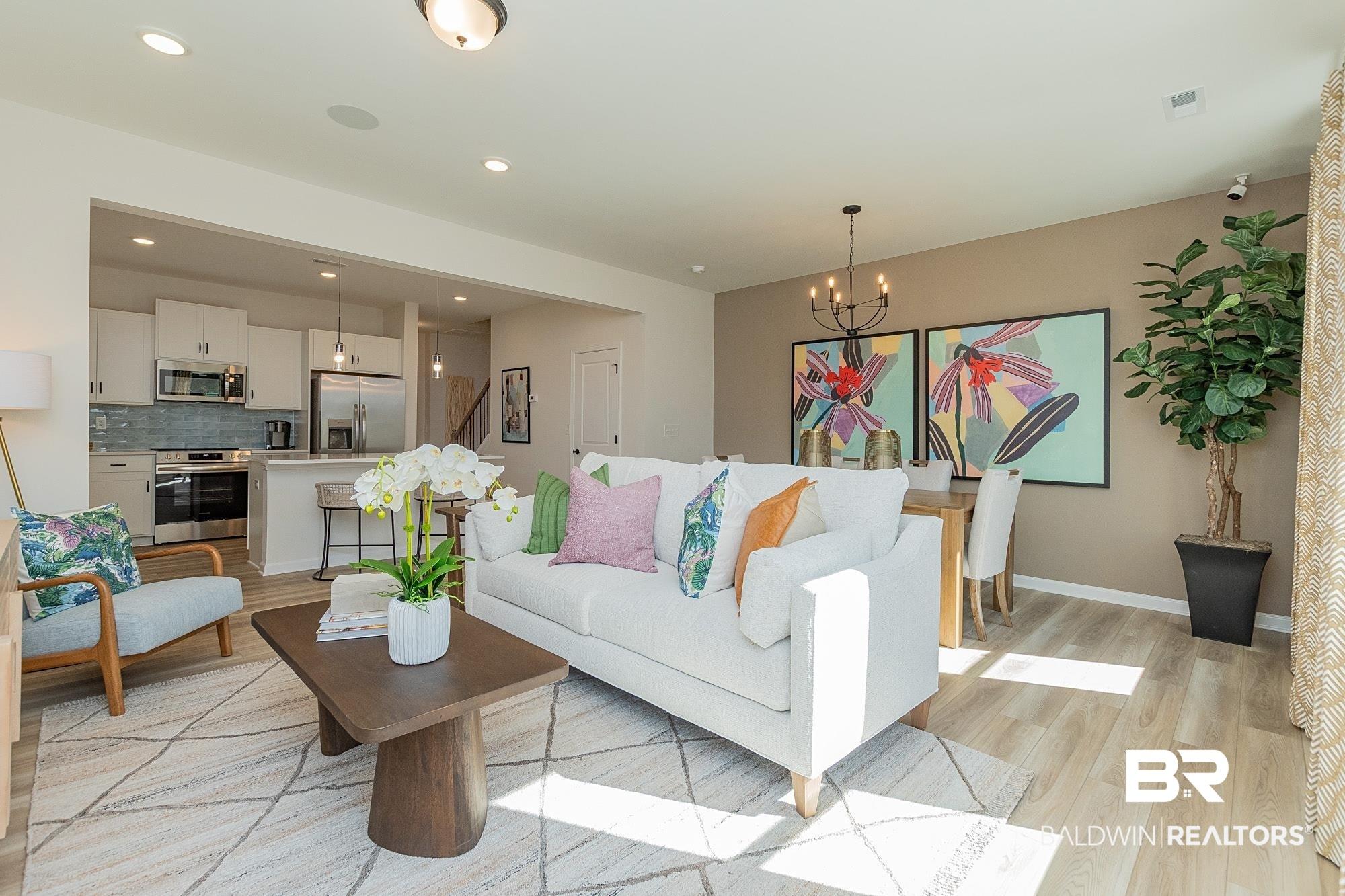 Image 4: Open-concept living space featuring light wood-finish flooring, recessed lighting, and a neutral wall palette