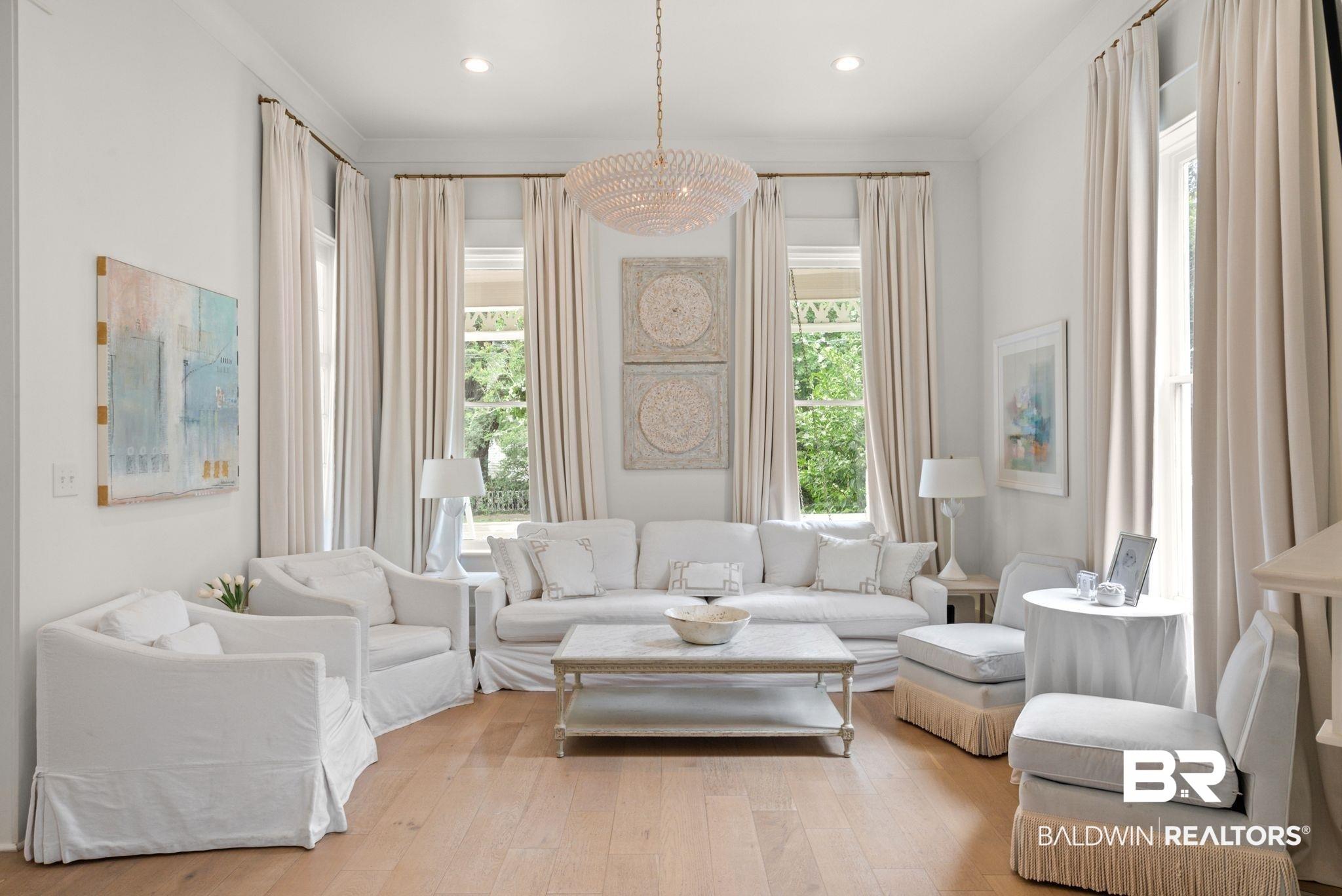 Image 2: Bright living area featuring light wood-finish flooring, recessed lighting, and a decorative chandelier