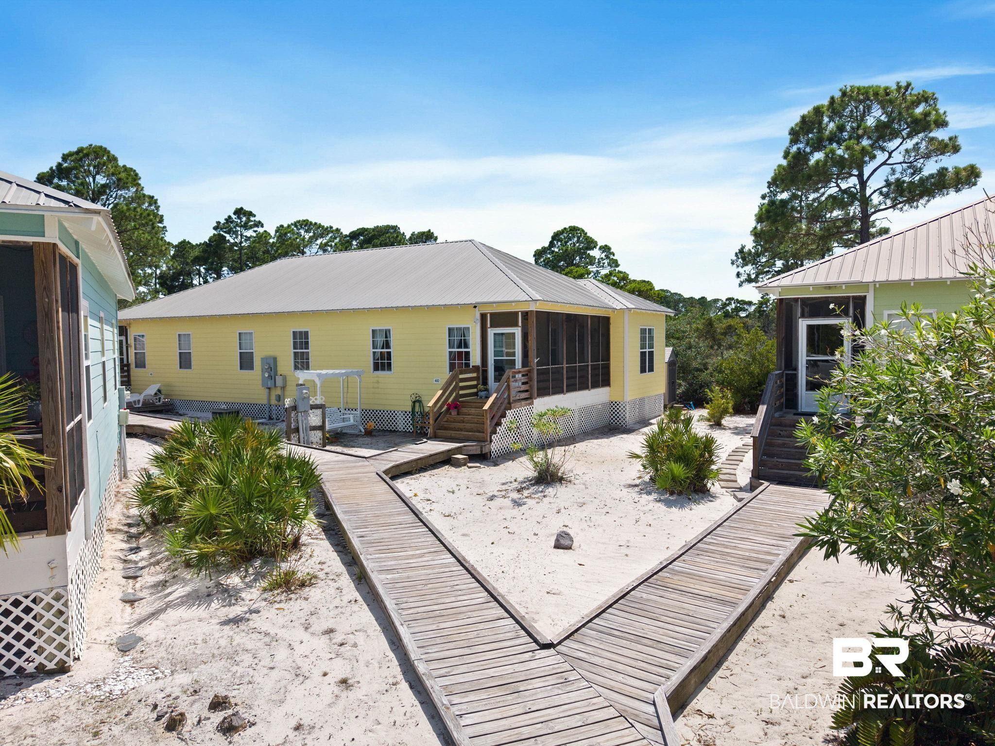 Image 2: Sandy landscape featuring multiple structures with light-colored siding and metal roofs