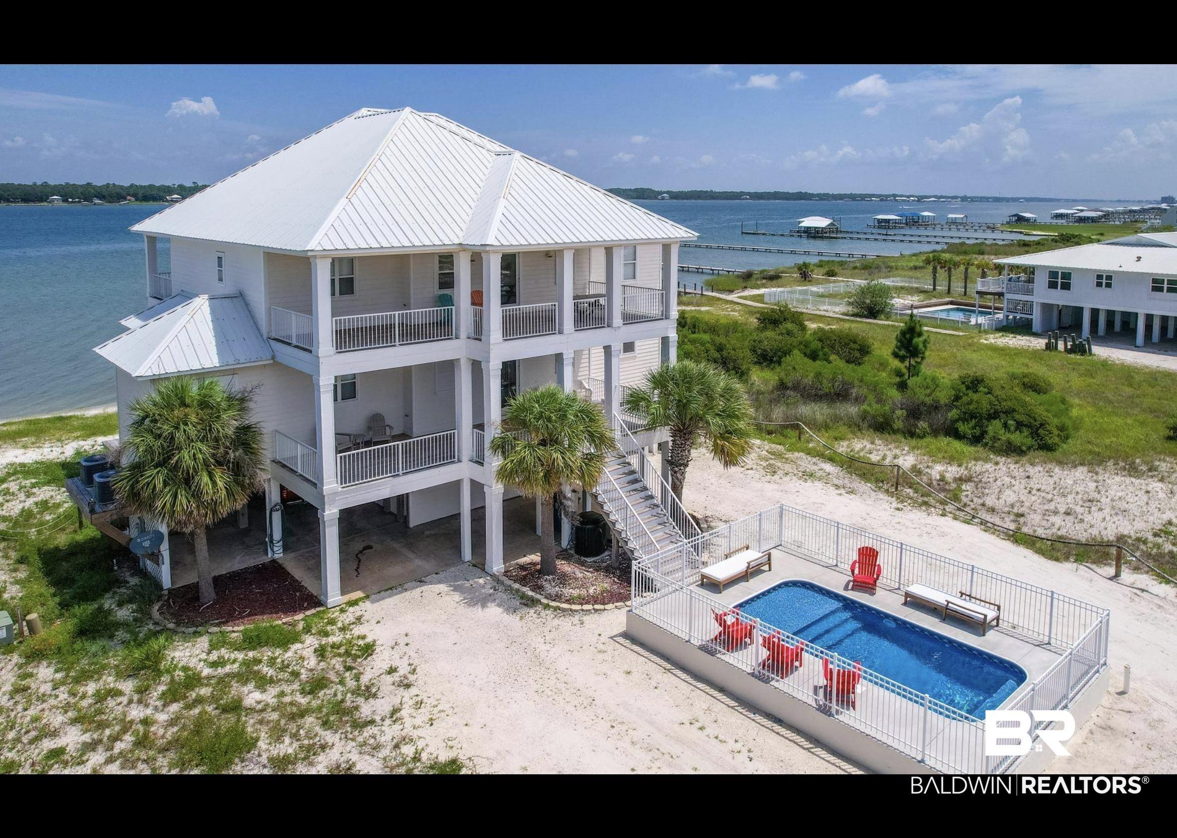 Image 3: Multi-level coastal residence featuring a white metal roof, multiple balconies with railings, and an exterior staircase
