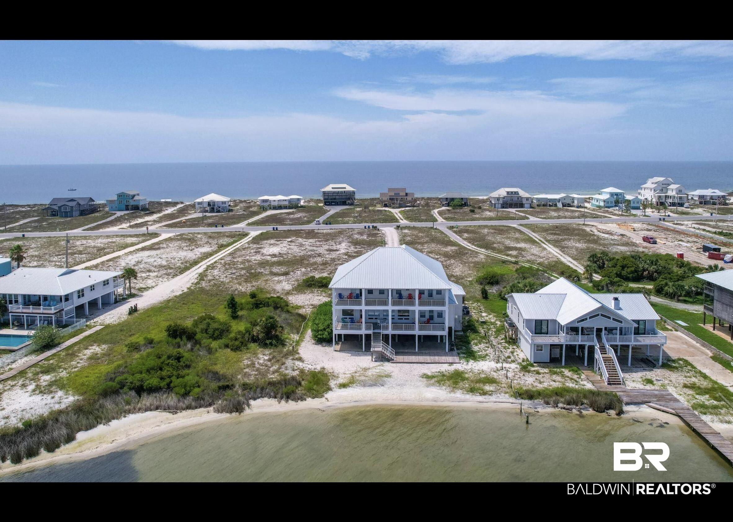 Image 4: Elevated coastal residence featuring a metal roof, multiple covered balconies, a private dock, and direct access to a tranquil waterway