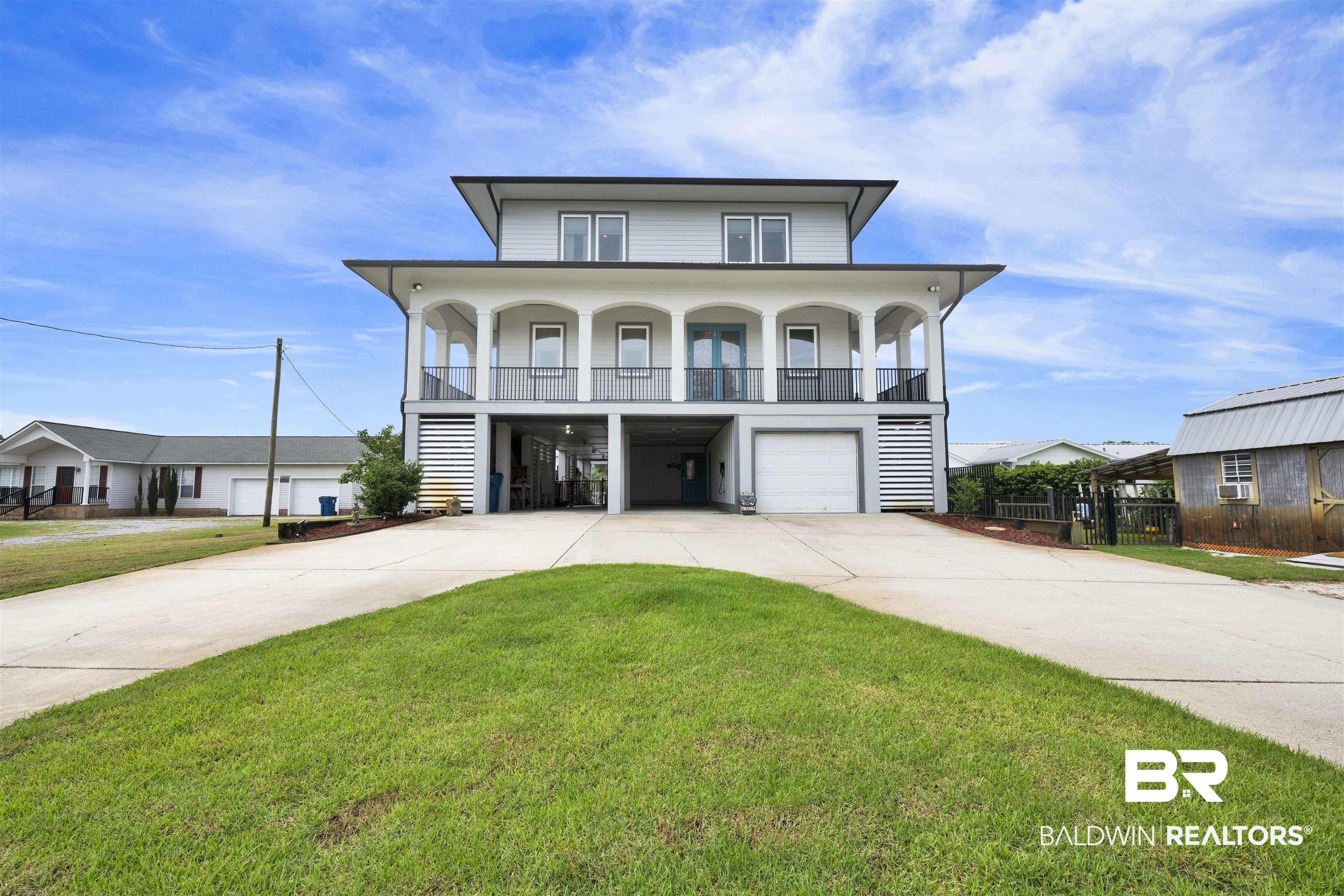 Image 1: Elevated coastal-style residence featuring a prominent covered balcony with arched openings and dark railings