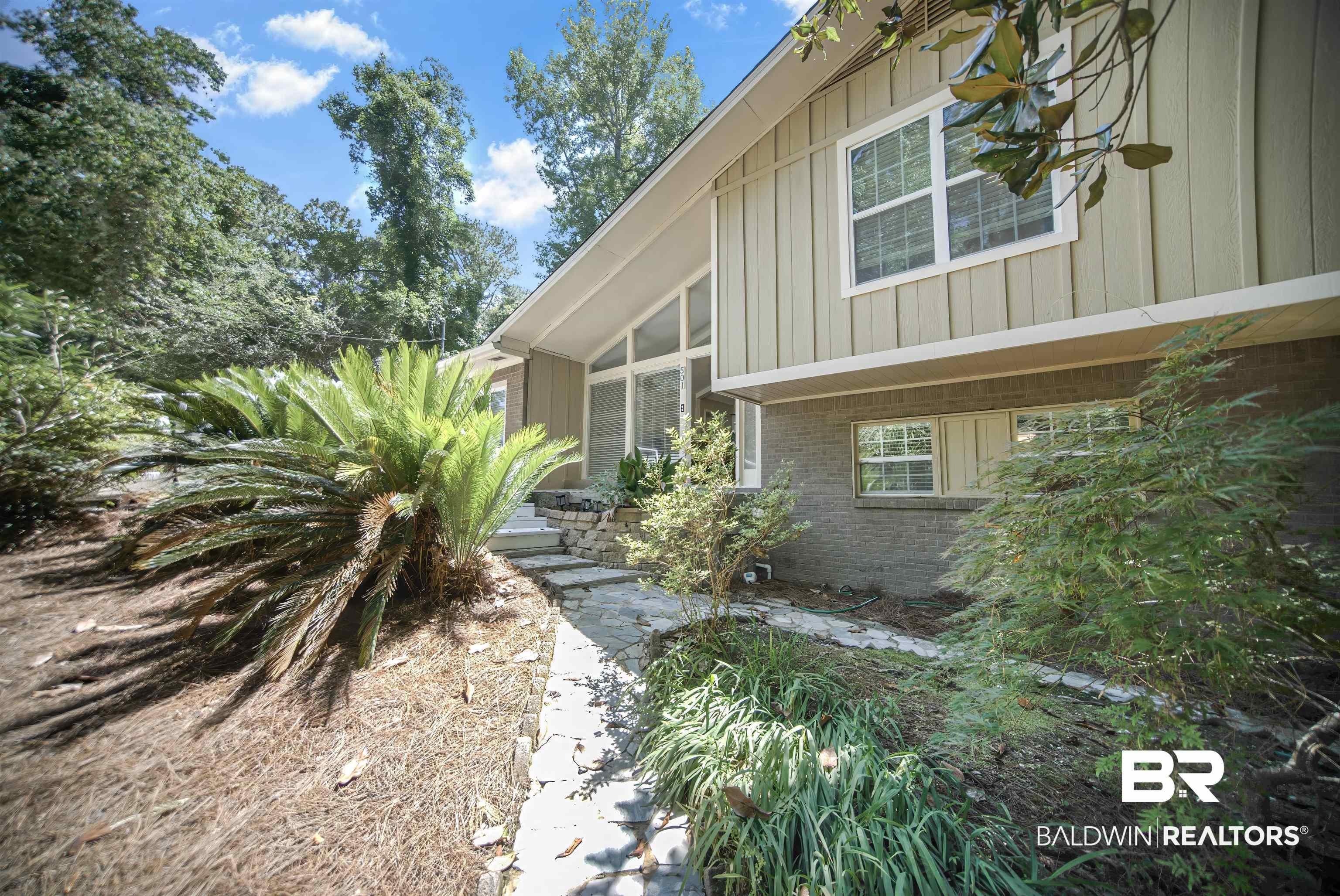 Image 2: Mid-century modern residence featuring board-and-batten siding, a partial brick facade, and a stone walkway