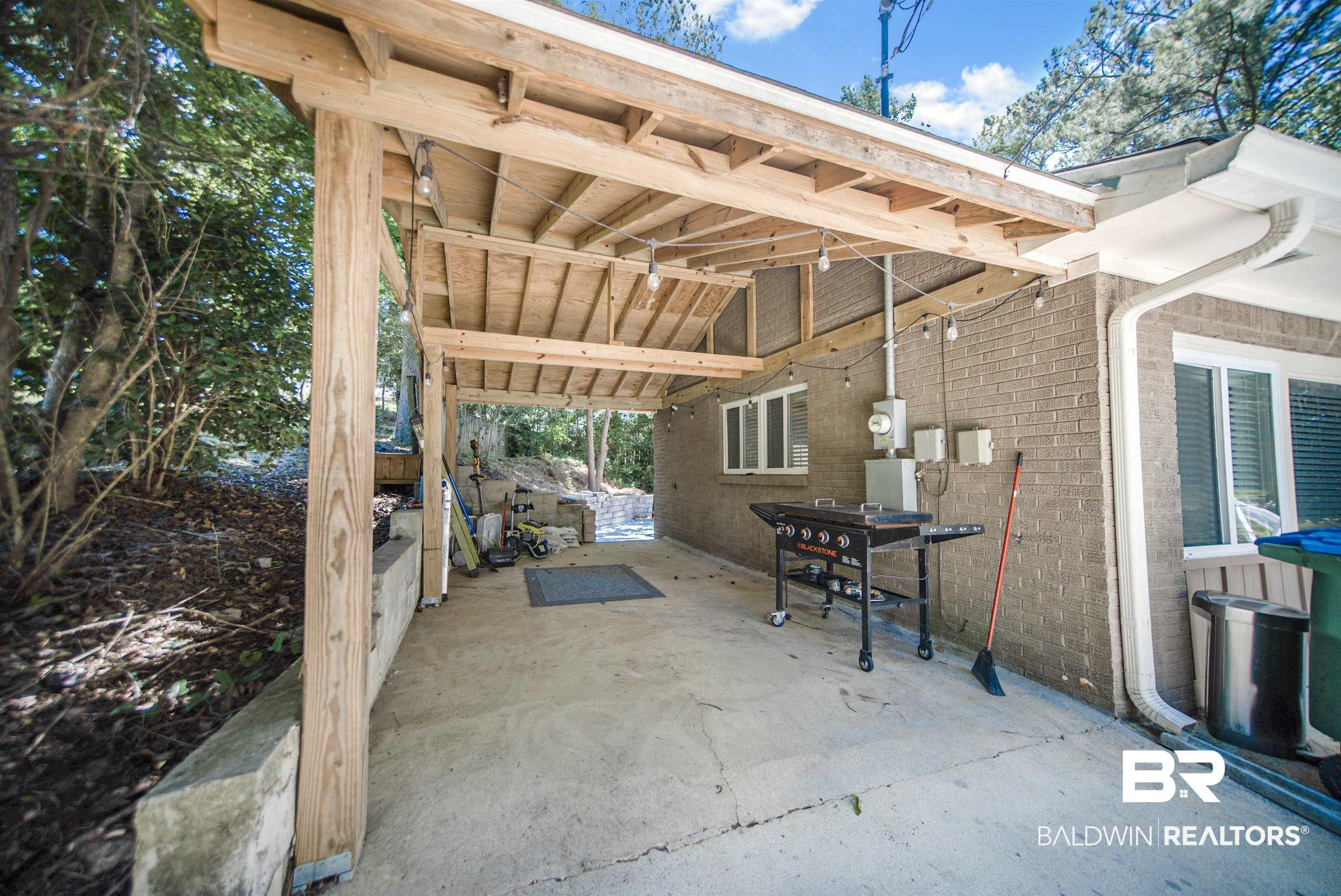 Image 3: Covered patio with a concrete surface and exposed wood beam ceiling
