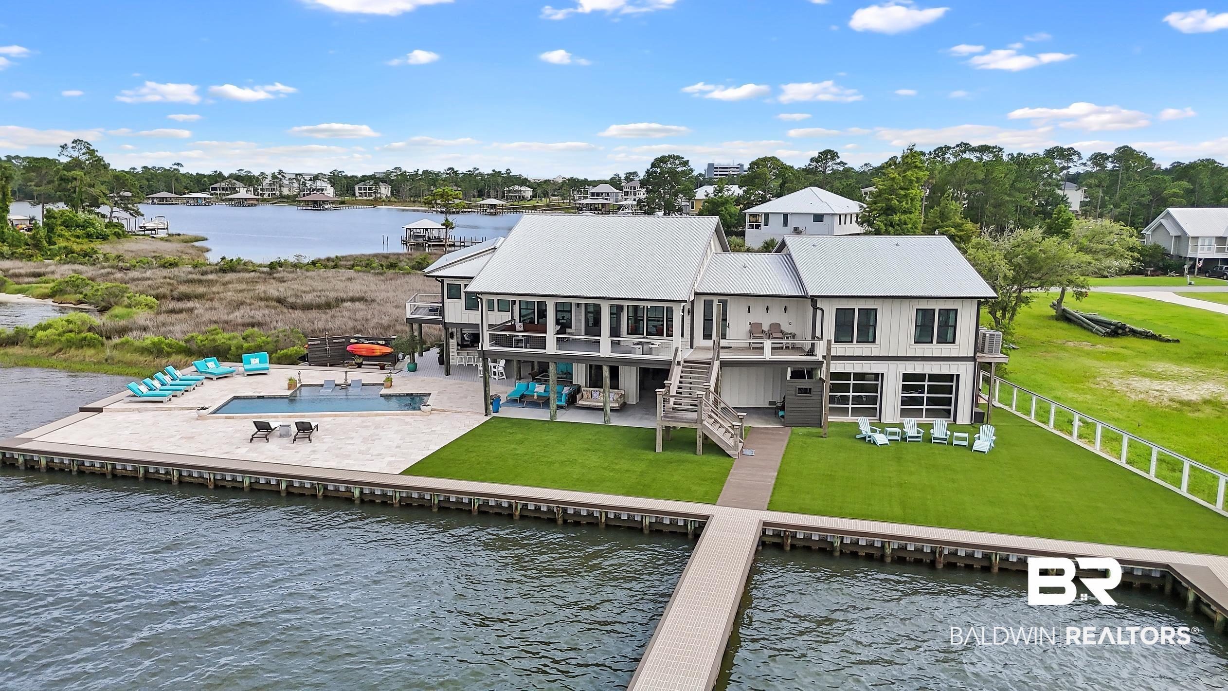 Image 3: Waterfront property featuring a private dock, an in-ground swimming pool, and an expansive paved patio