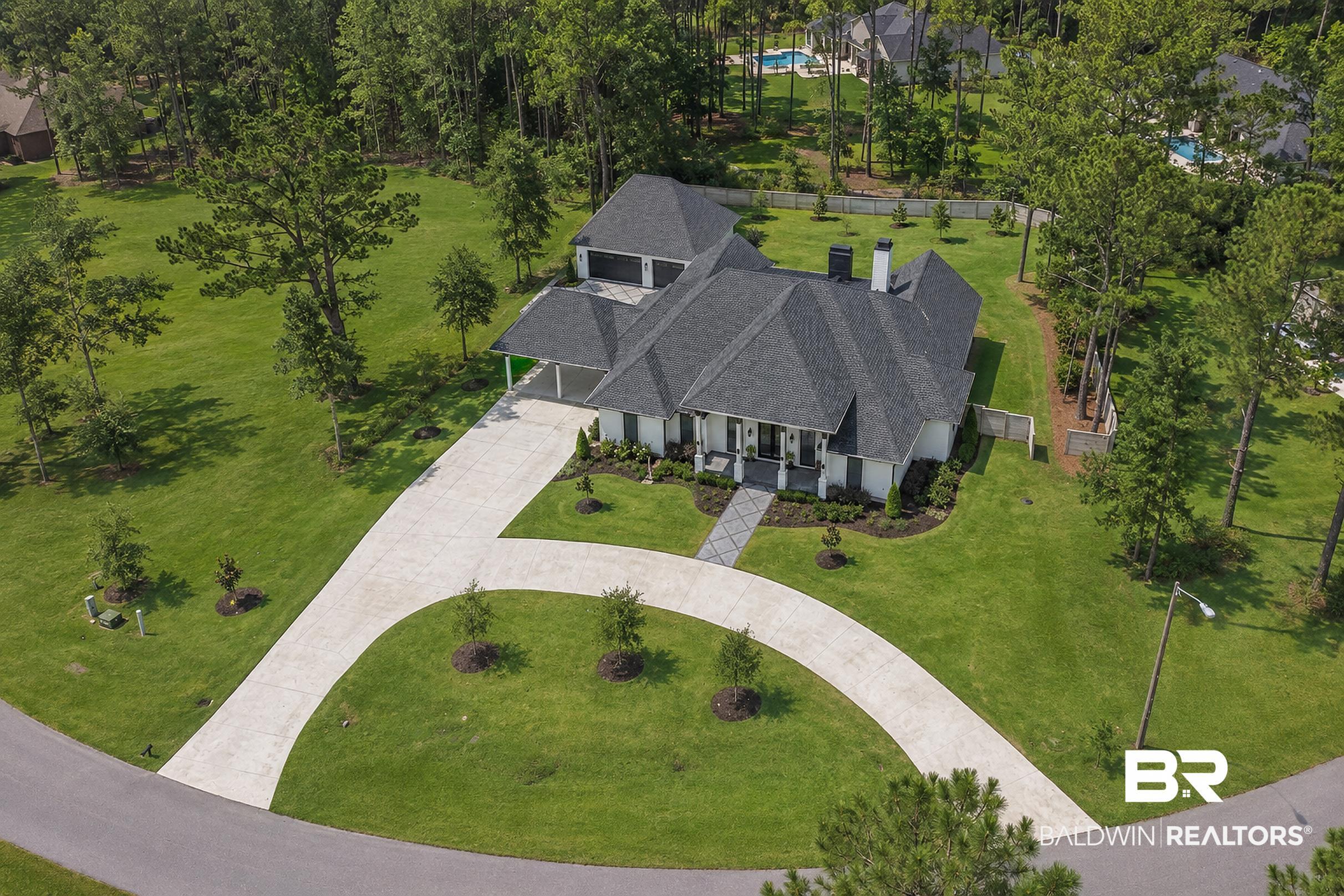 Image 3: White exterior residence with a dark shingled roof and a multi-car concrete driveway