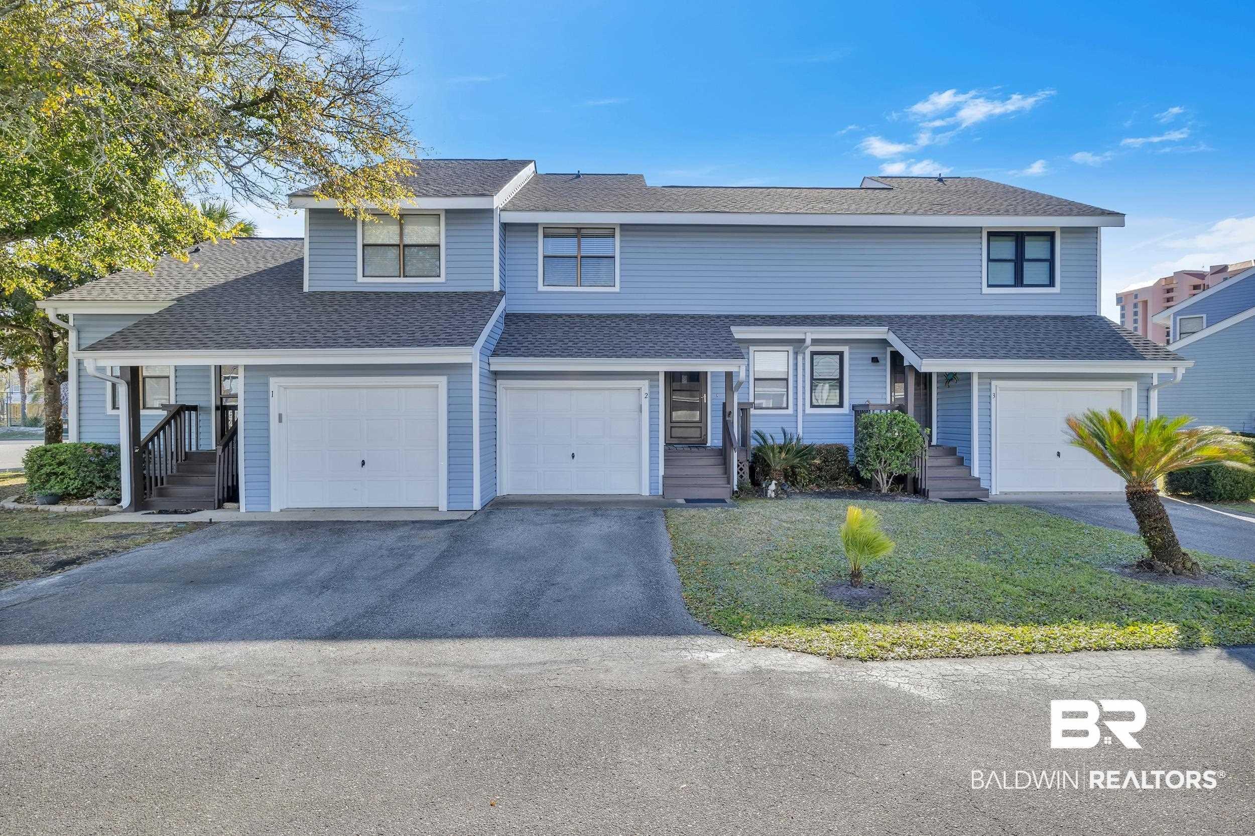 Image 3: Light blue siding exterior with multiple garage doors and individual entrance stairs