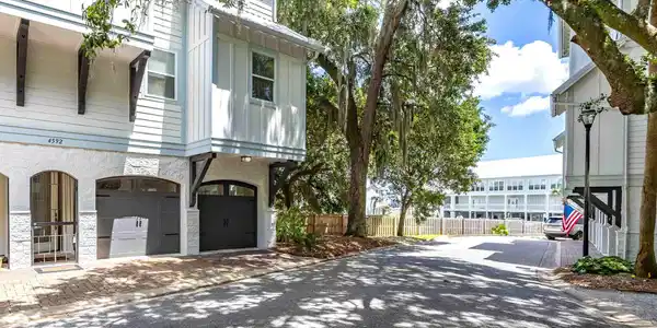 Image 2: Multi-level residence featuring white siding, a stucco first story, and arched garage doors