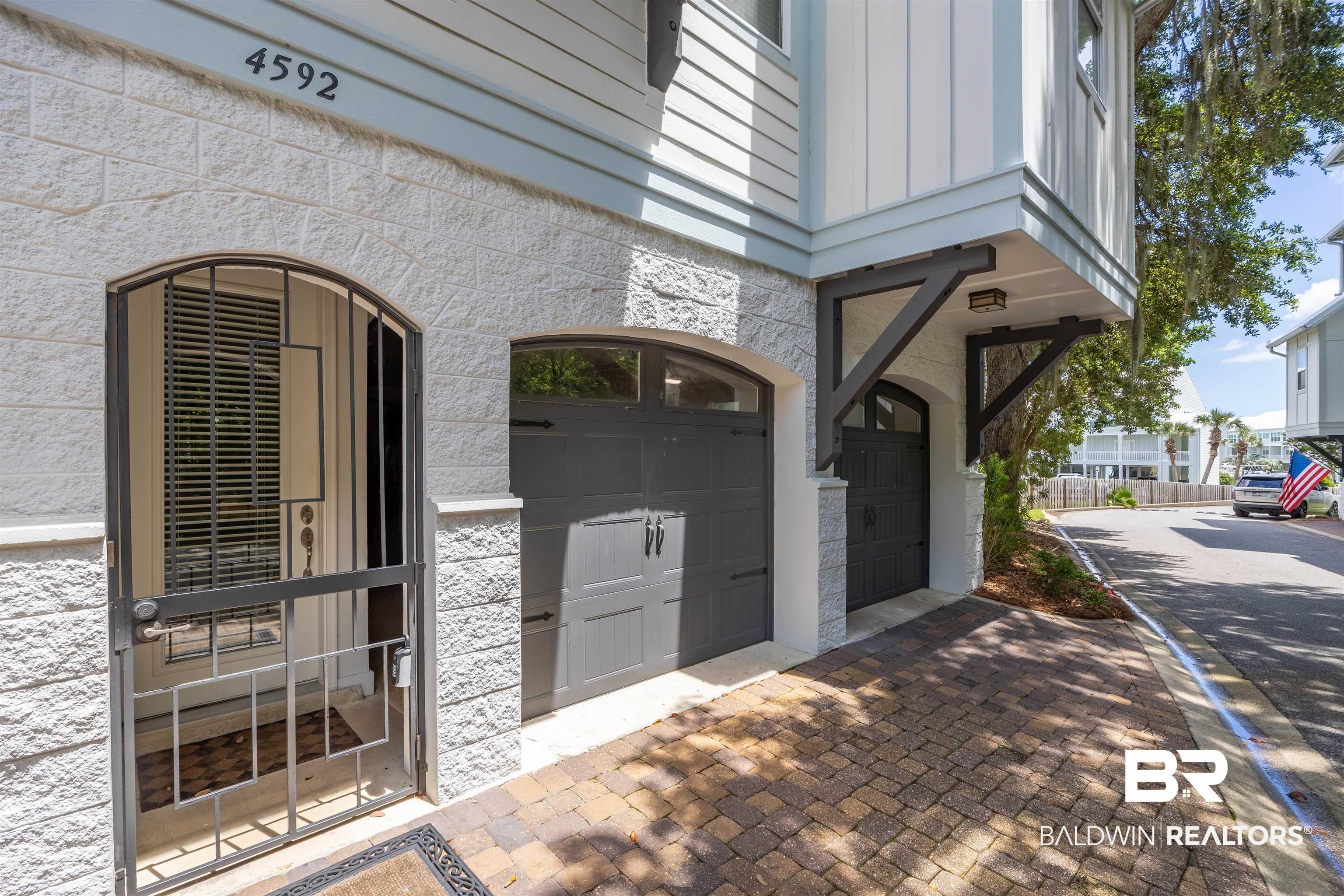 Image 3: Light-colored block exterior with dark gray garage doors and a decorative wrought iron security gate