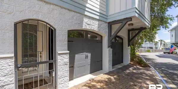 Image 3: Light-colored block exterior with dark gray garage doors and a decorative wrought iron security gate