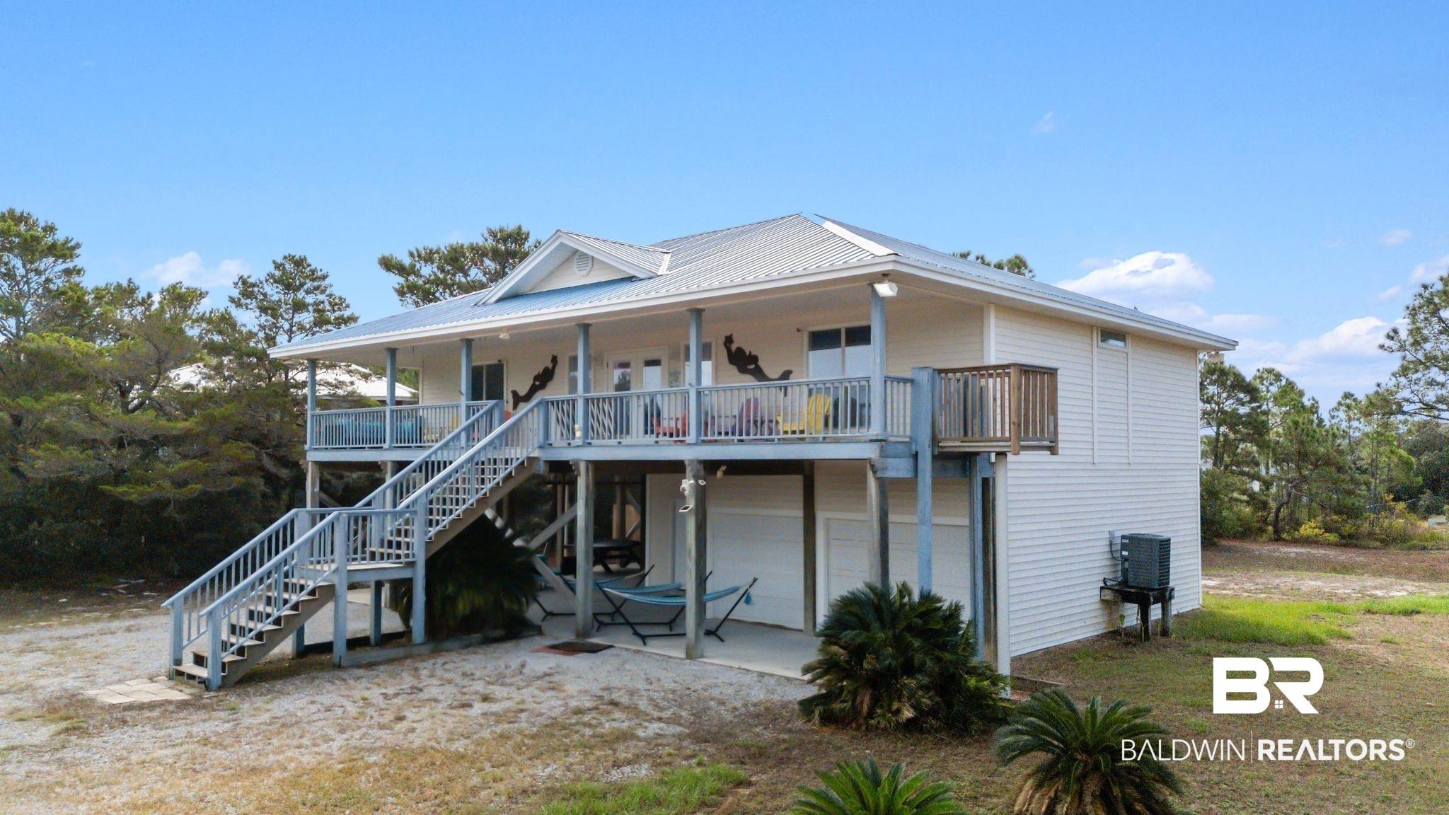 Image 2: Elevated residence featuring a metal roof, extensive wrap-around deck, and ground-level covered patio