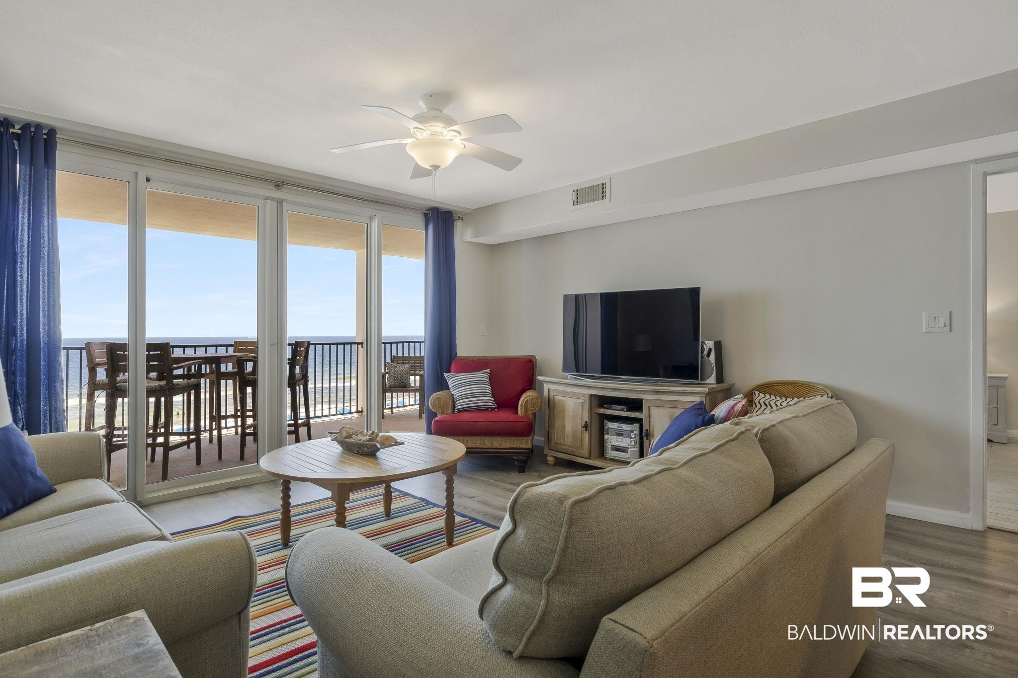 Image 4: Spacious living area featuring expansive glass doors opening to an outdoor balcony