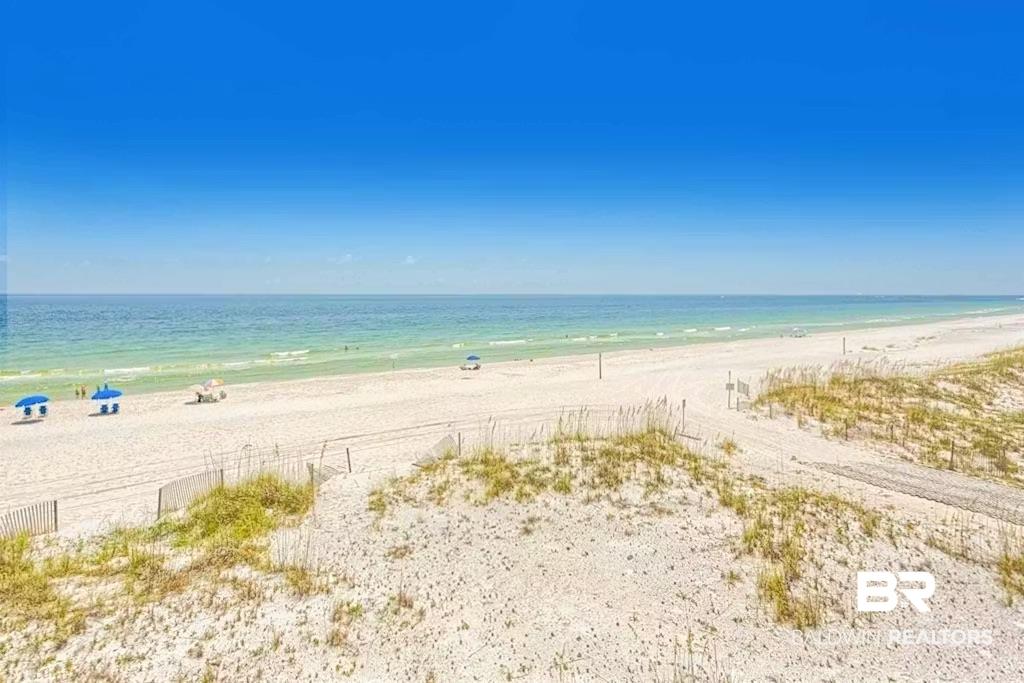 Image 4: Expansive sandy beach with clear blue-green ocean waters