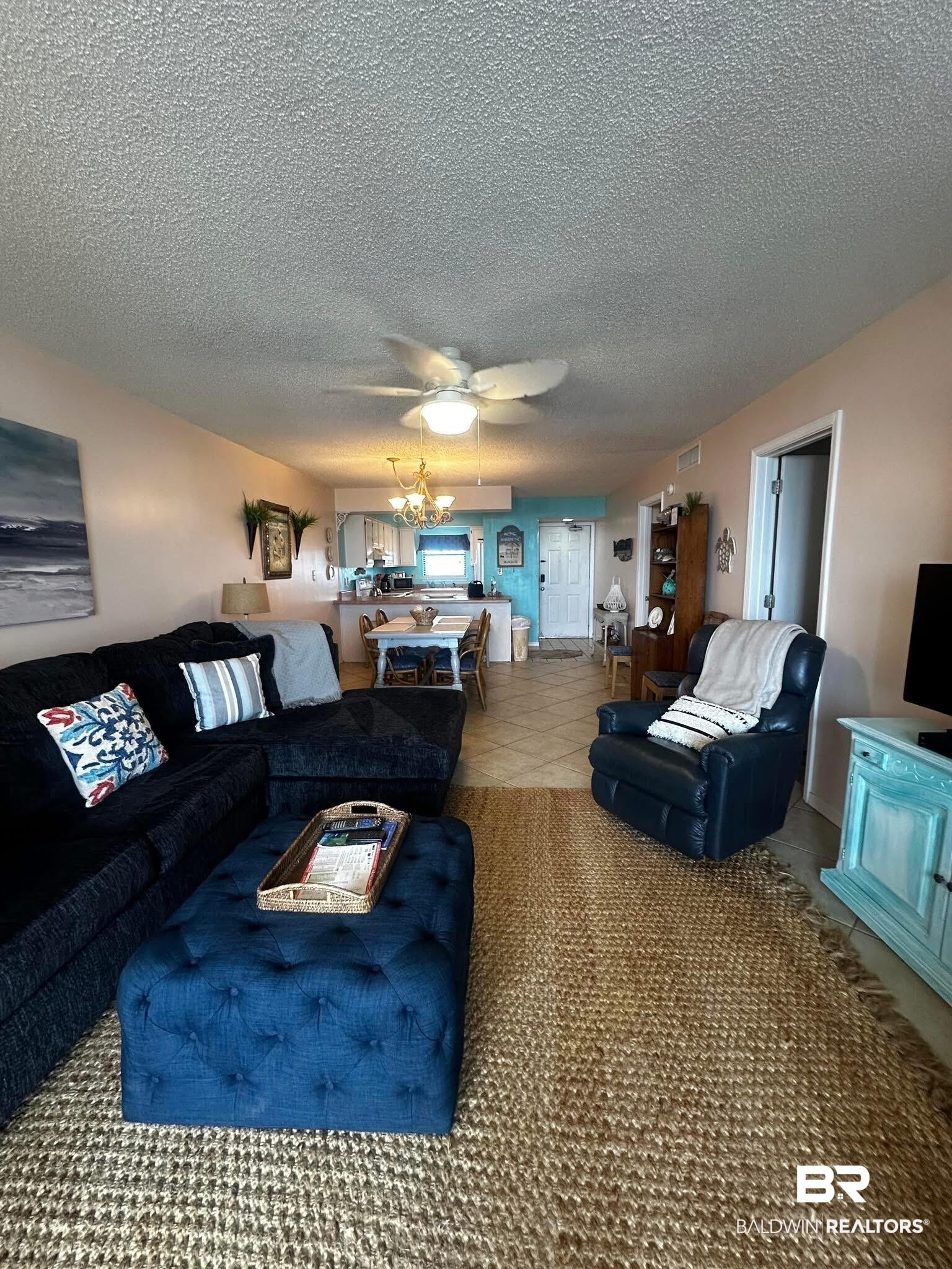 Image 3: Open-concept living area with textured ceilings, ceiling fan, and tile flooring