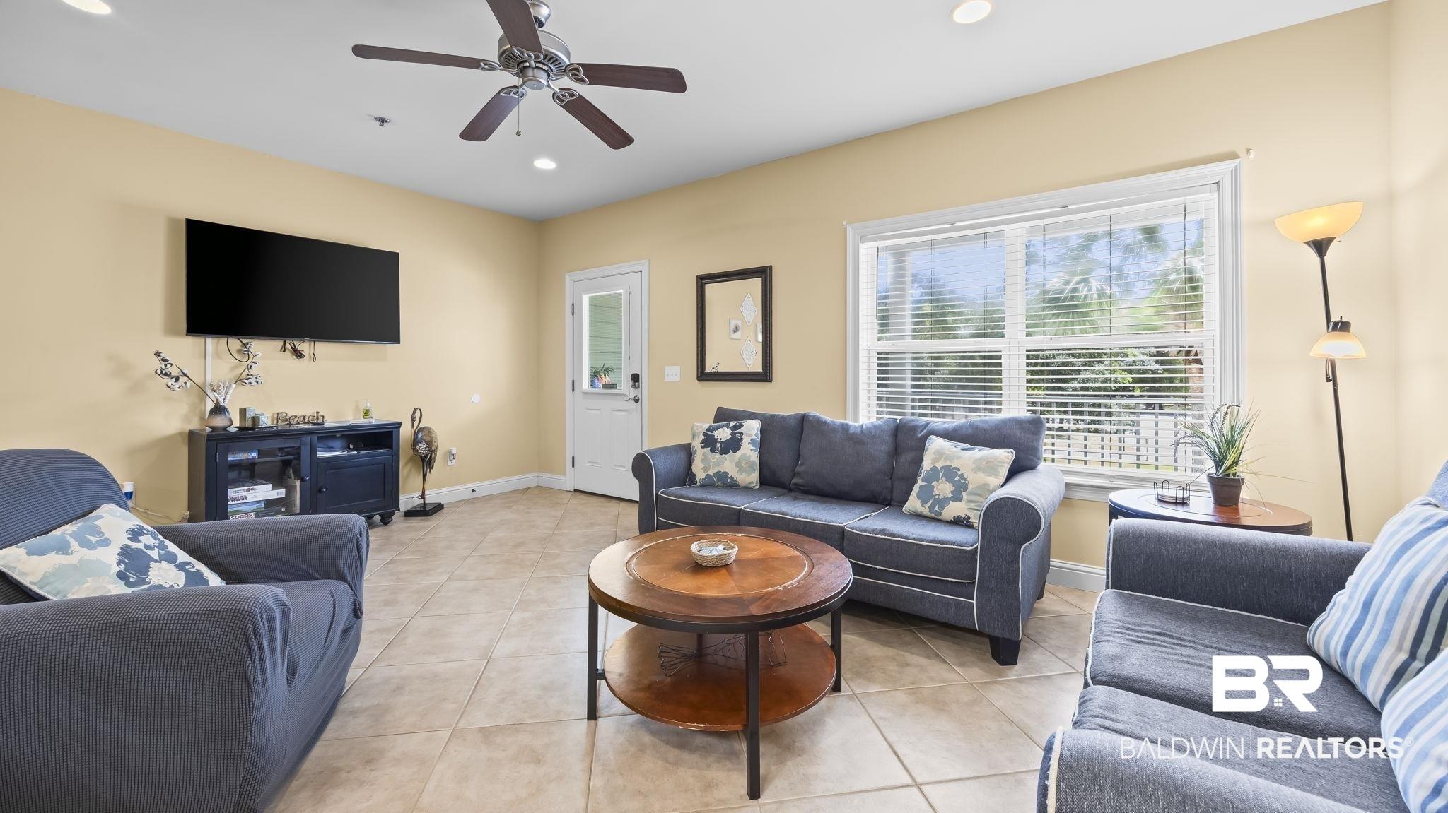 Image 4: Living area with recessed lighting, light tile patterned floors, and ceiling fan