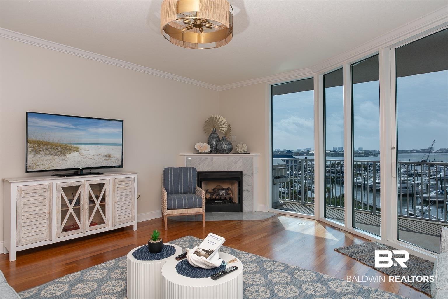 Image 2: Living area featuring wood-finish flooring, a corner fireplace with a marble-finish surround, and a decorative ceiling light fixture