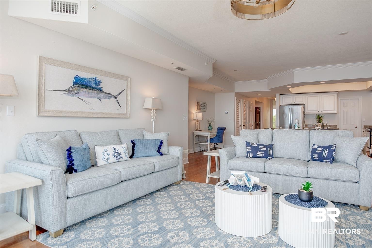 Image 3: Open-concept living space featuring wood-finish flooring, a patterned area rug, recessed lighting, and crown molding