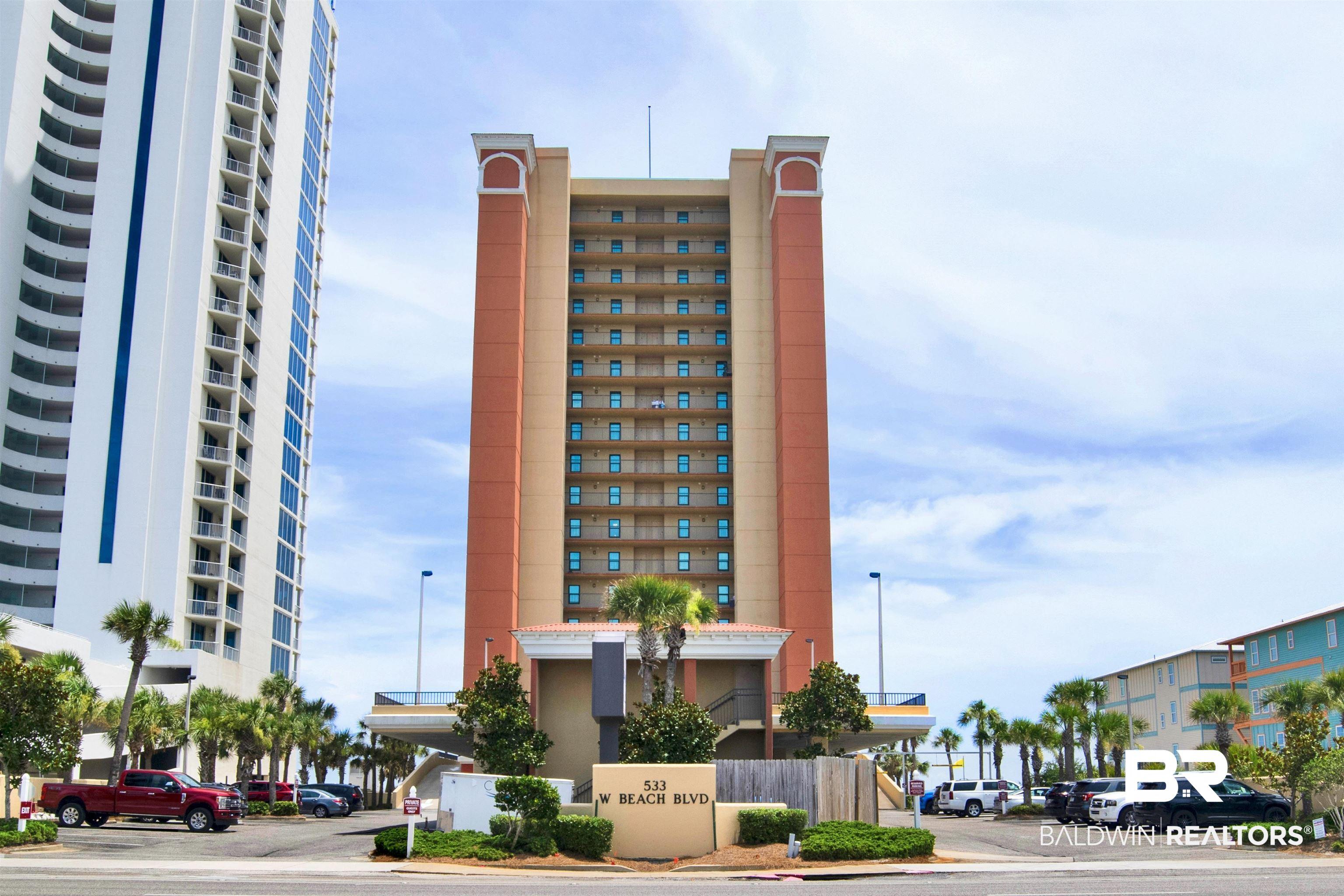 Image 2: Multi-story building featuring numerous private balconies, a designated entrance, and a surrounding palm tree landscape