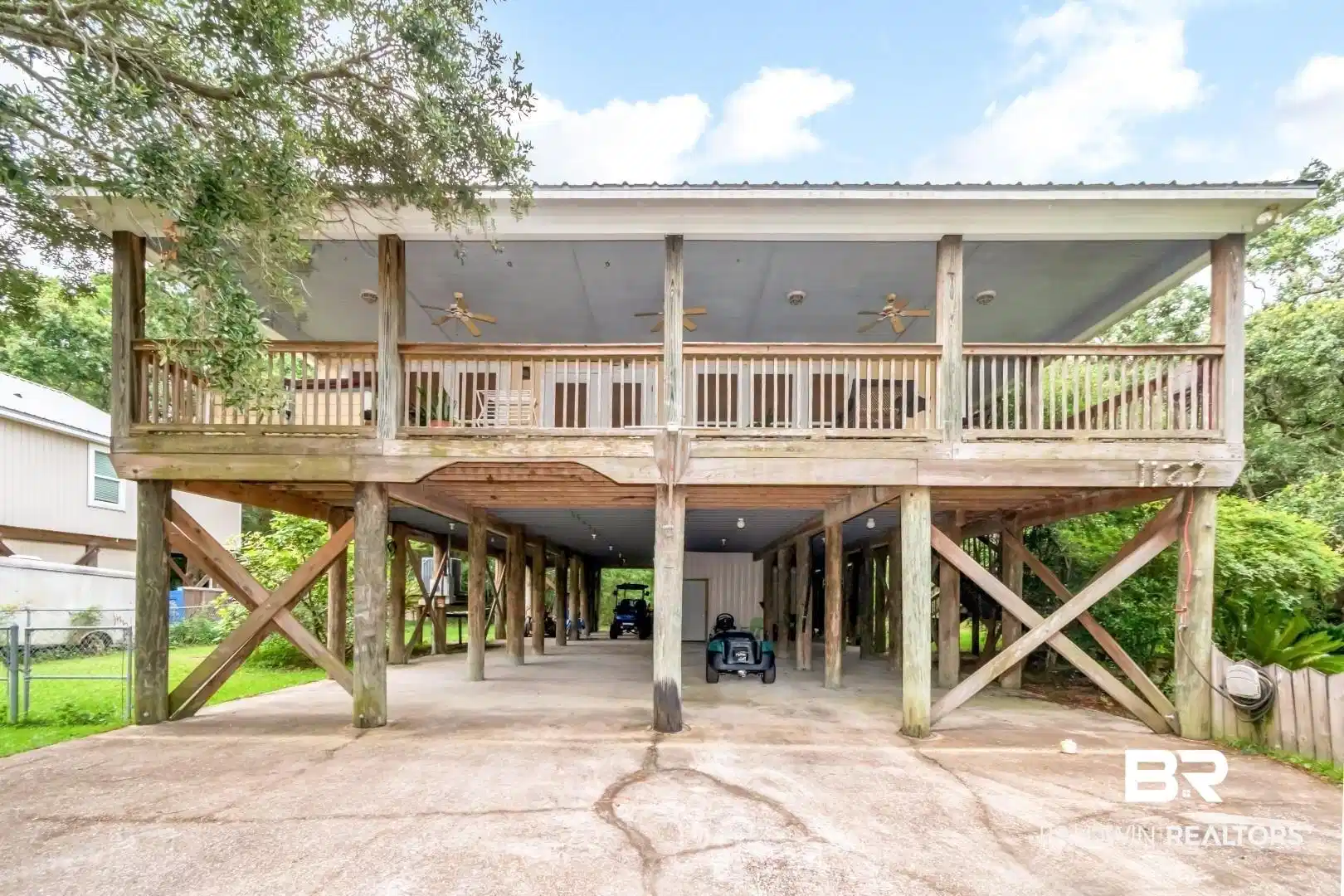 Image 1: Elevated structure featuring a spacious covered porch with wood railings and multiple ceiling fans