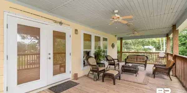 Image 2: Expansive wood deck with a covered ceiling, dual ceiling fans, and a light yellow exterior wall