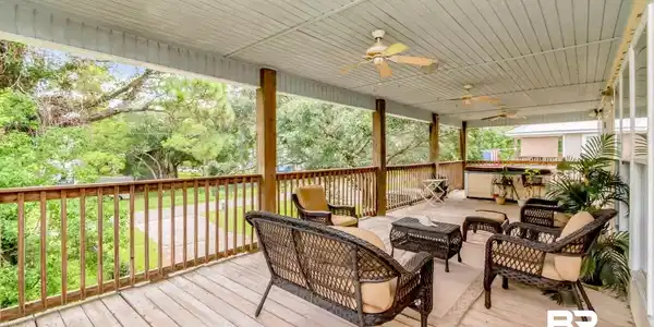 Image 4: Expansive covered wood-decked patio featuring a slatted wood ceiling, multiple ceiling fans, wooden railings, and multiple support columns