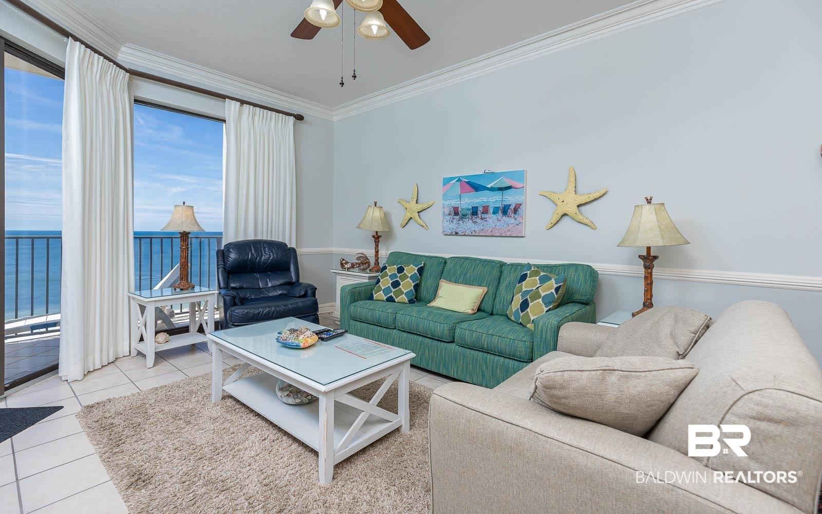 Image 3: Living area with tile patterned flooring, a water view, ornamental molding, and a ceiling fan