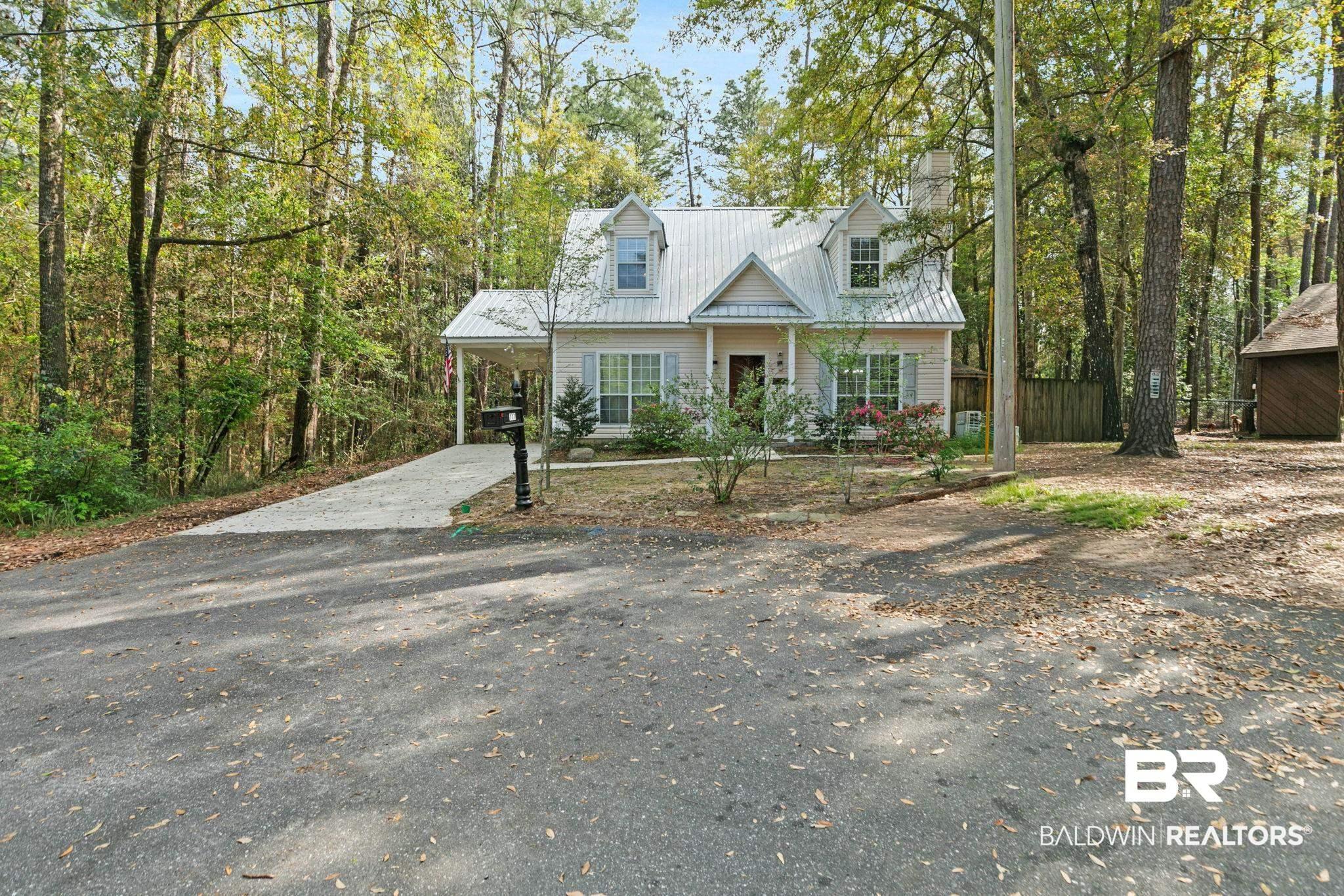 Image 2: Cape cod home featuring asphalt driveway, a metal roof, an attached carport, a porch, and a chimney