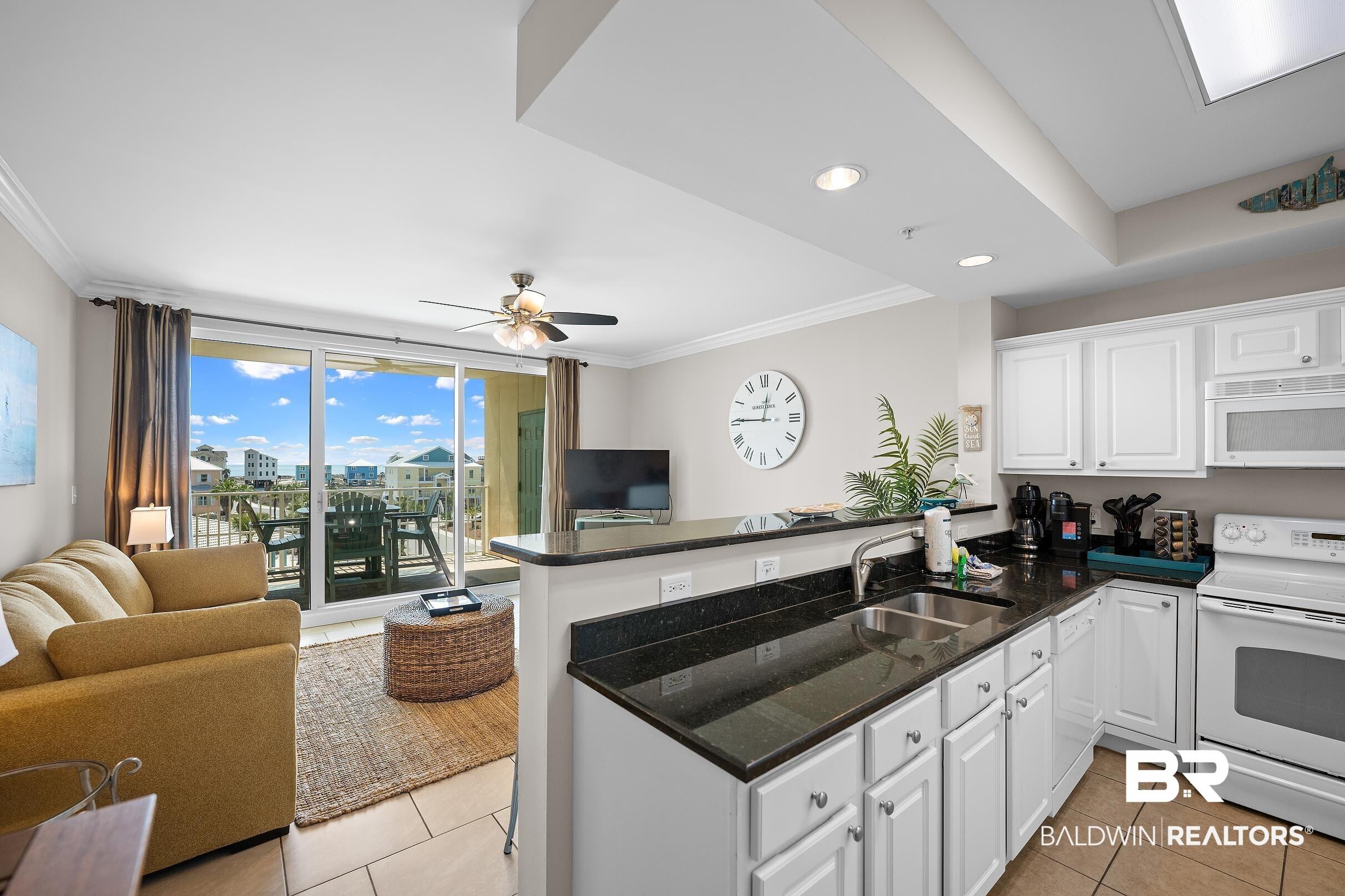 Image 2: Kitchen featuring open floor plan, white appliances, a peninsula, white cabinetry, and ceiling fan