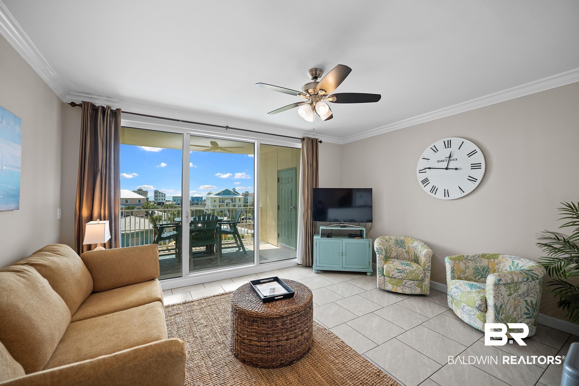 Image 3: Living room with crown molding, a ceiling fan, light tile patterned floors, and floor to ceiling windows
