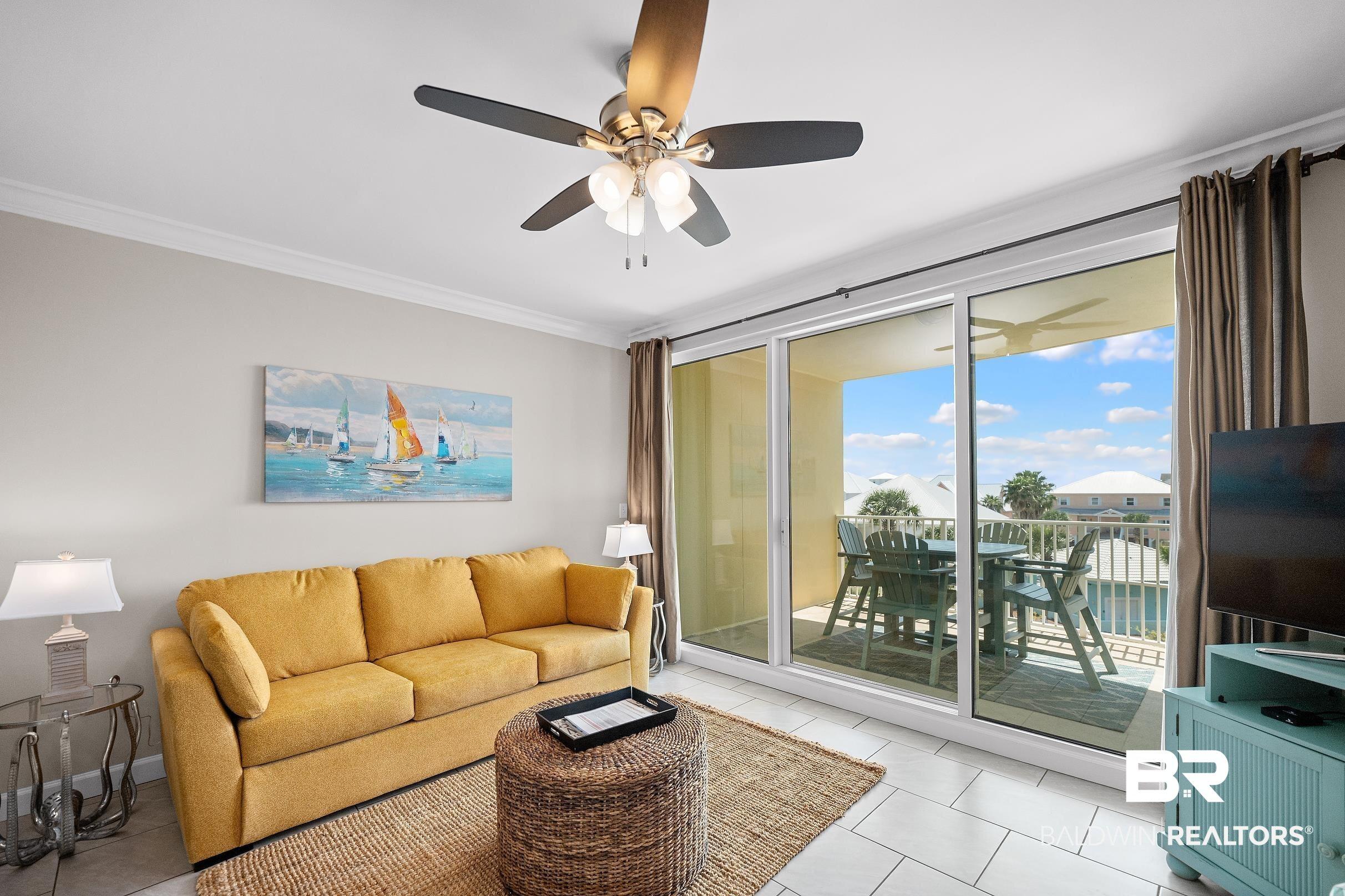 Image 4: Living room featuring a ceiling fan, crown molding, light tile patterned flooring, and expansive windows