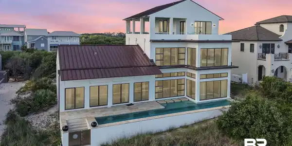 Image 3: Back of property at dusk with a balcony and stucco siding