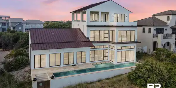 Image 4: Back of property featuring a balcony, stucco siding, and metal roof