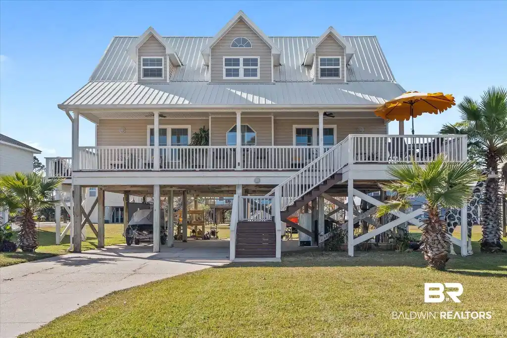Image 1: Beach home with stairs, a carport, a front lawn, and a porch