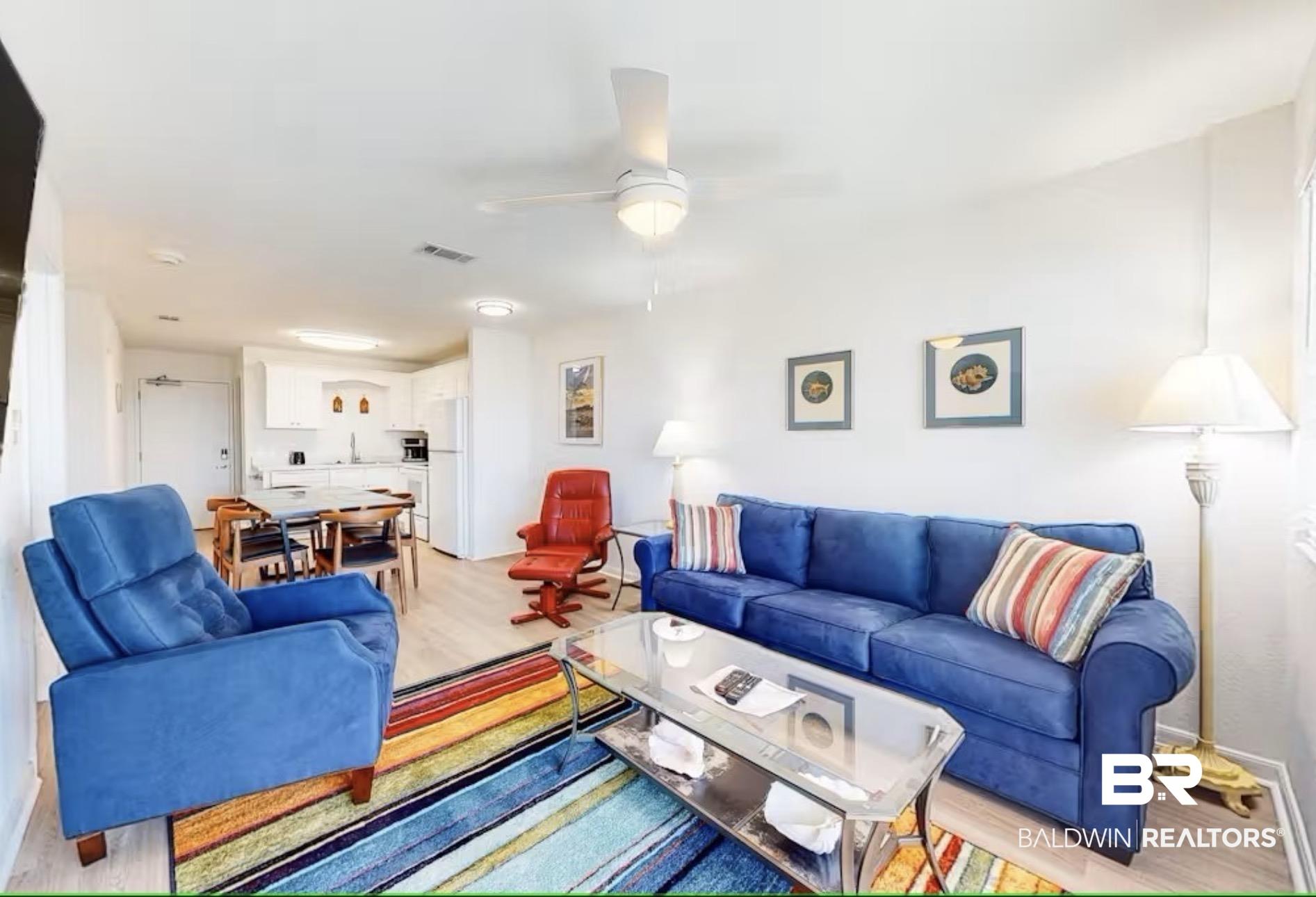Image 2: Open-concept living space featuring wood-finish flooring, white walls, and a ceiling fan with integrated lighting