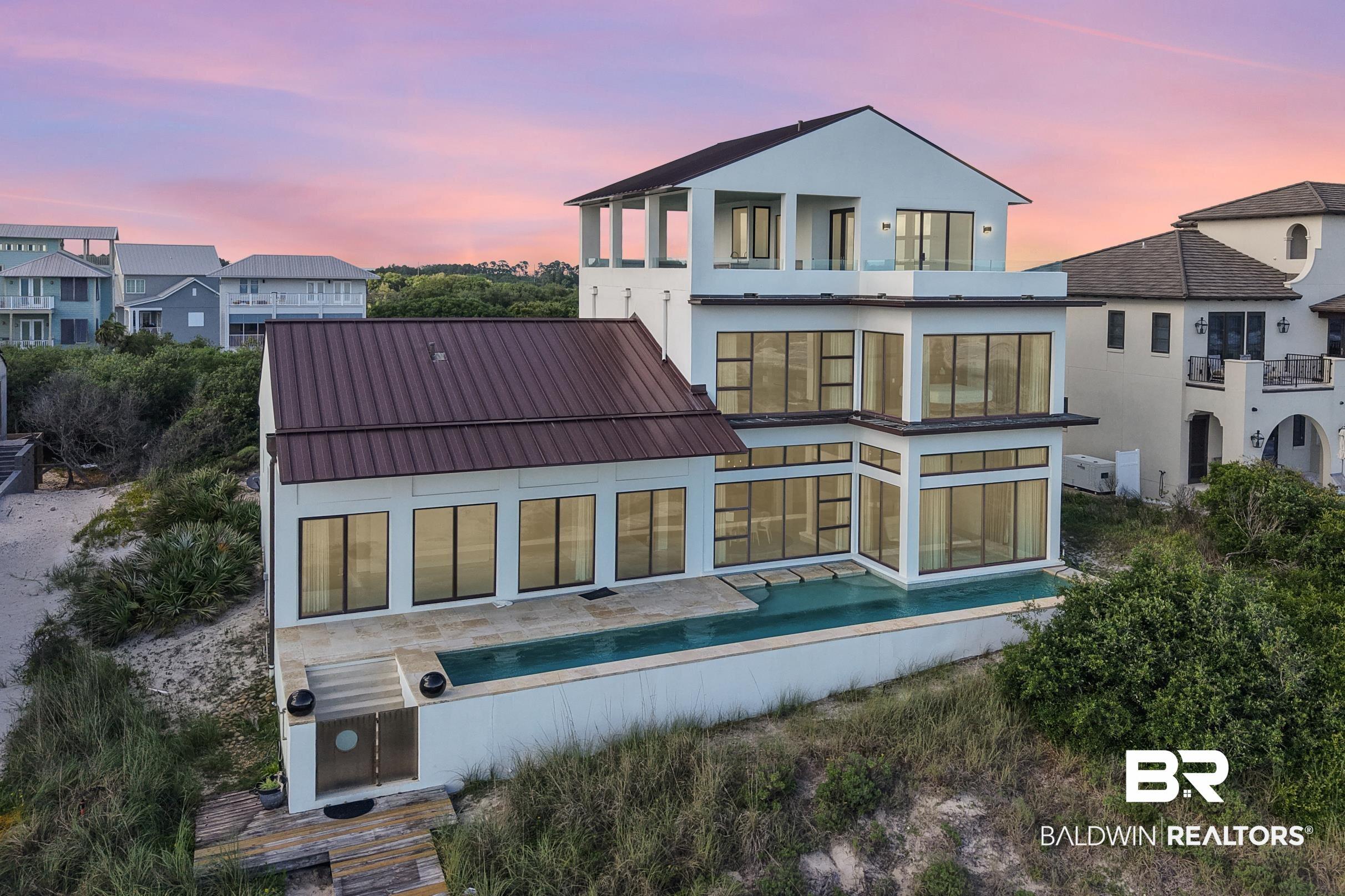 Image 3: Back of property at dusk with a balcony and stucco siding