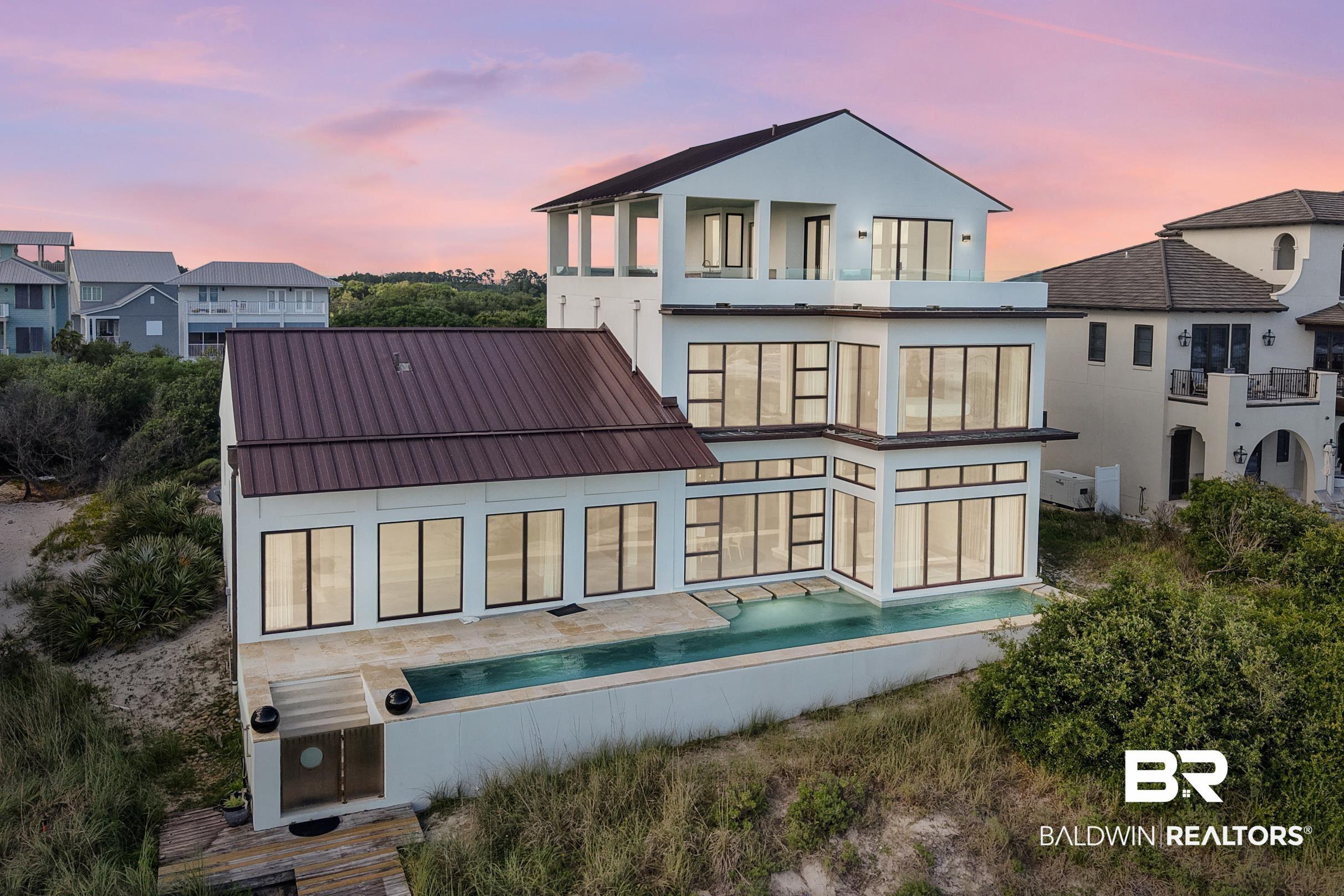 Image 4: Back of property featuring a balcony, stucco siding, and metal roof