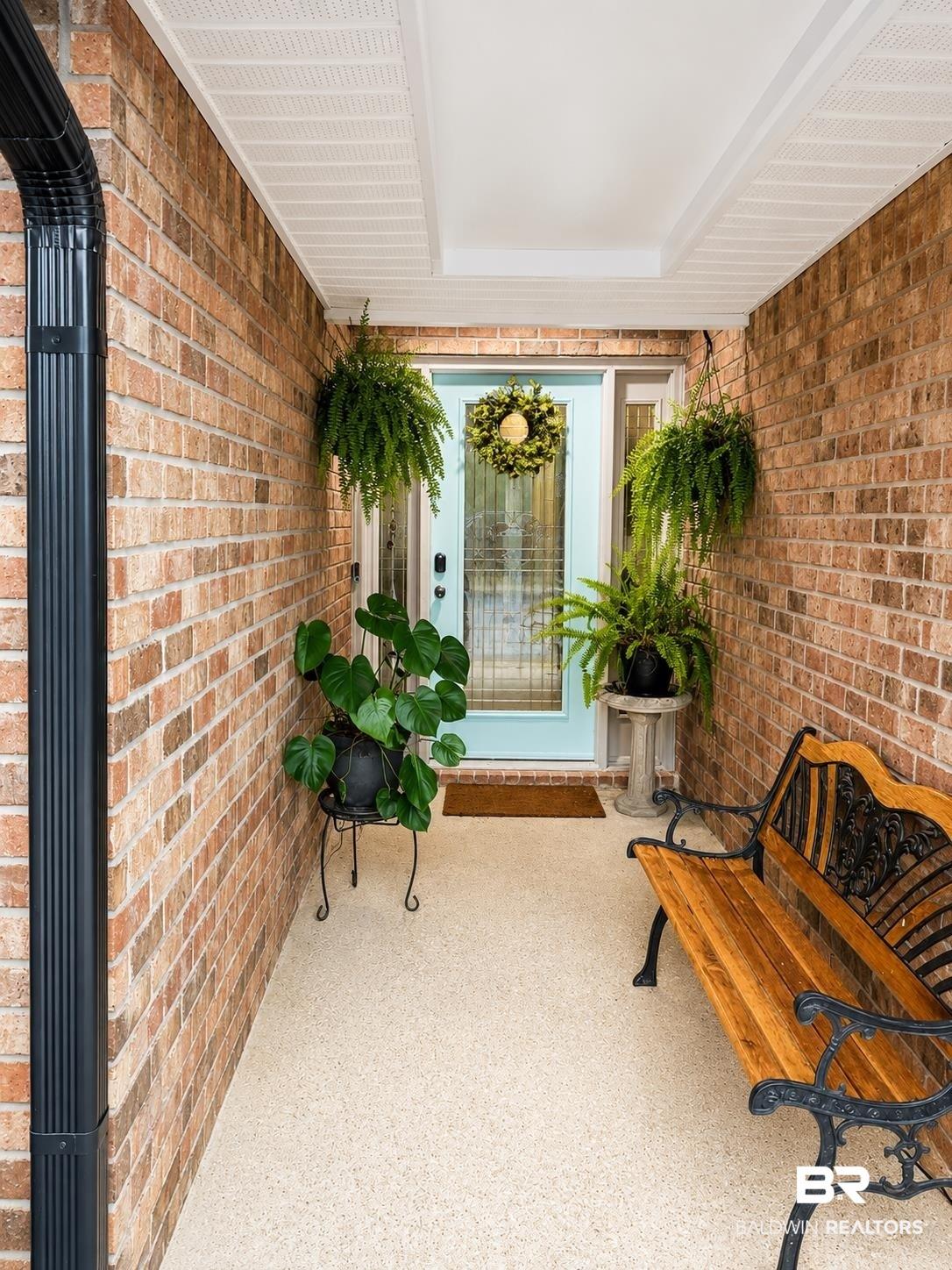Image 3: Covered front entry featuring a light blue door with sidelights, brick exterior, speckled concrete flooring, and a white soffit ceiling