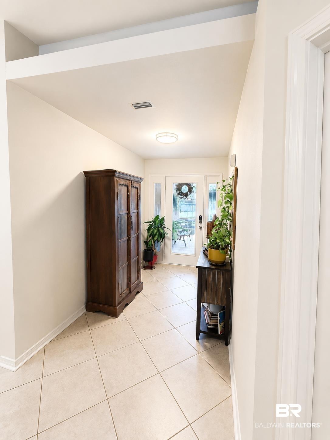 Image 4: Entryway with light-colored tile flooring, white walls, and a ceiling with an open beam feature