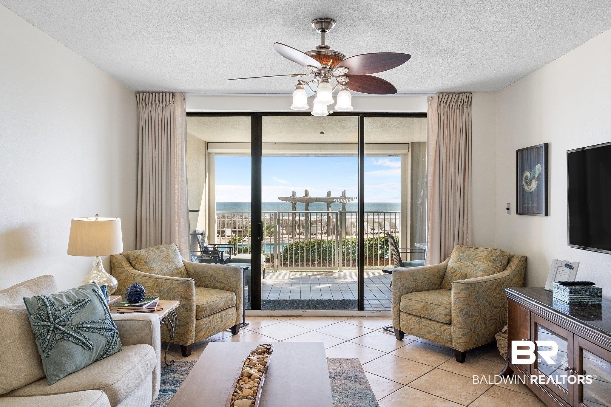 Image 2: Living room featuring ceiling fan, tile patterned flooring, a textured ceiling, and floor to ceiling windows