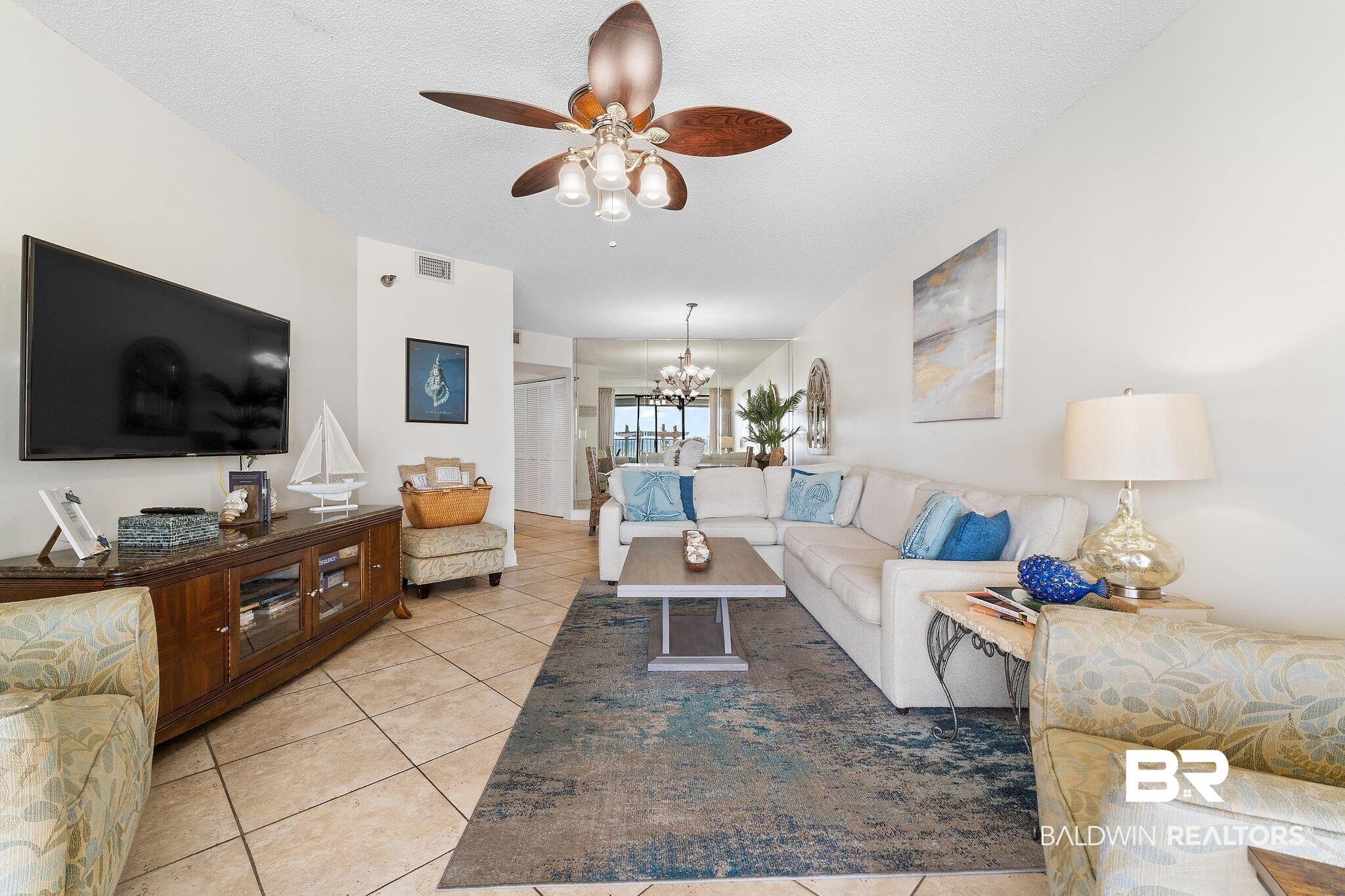 Image 3: Living area with hanging lights, a ceiling fan, light tile patterned floors, and a textured ceiling