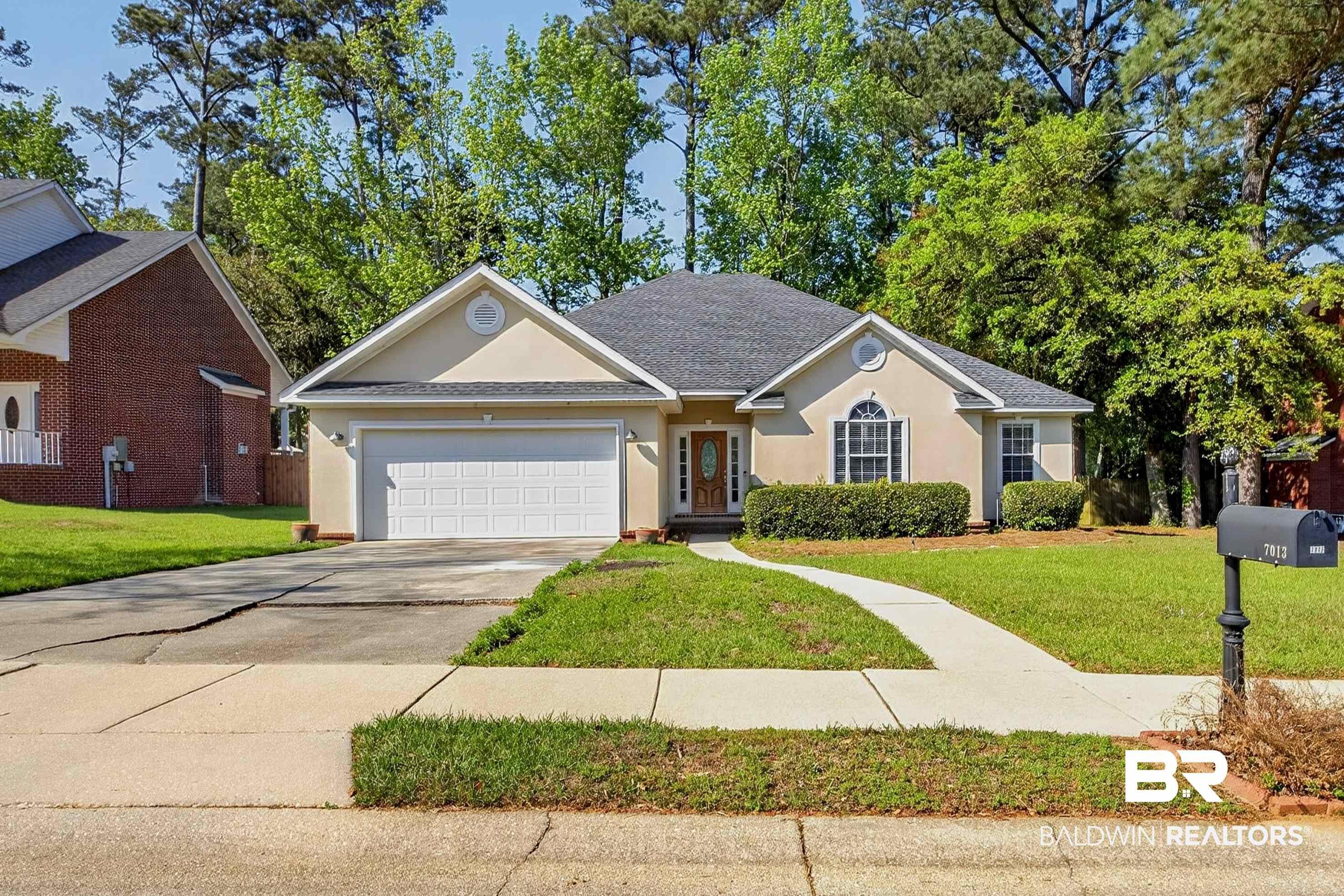 Image 4: Stucco exterior with a dark shingle roof, featuring a two-car garage, established front lawn, concrete driveway, and a front walkway