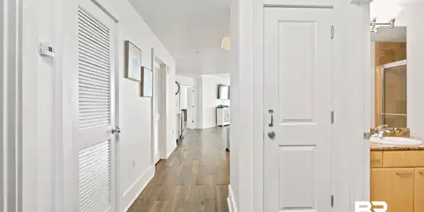 Image 3: Hallway featuring wood-finish flooring, white paneled doors, and contemporary wall art