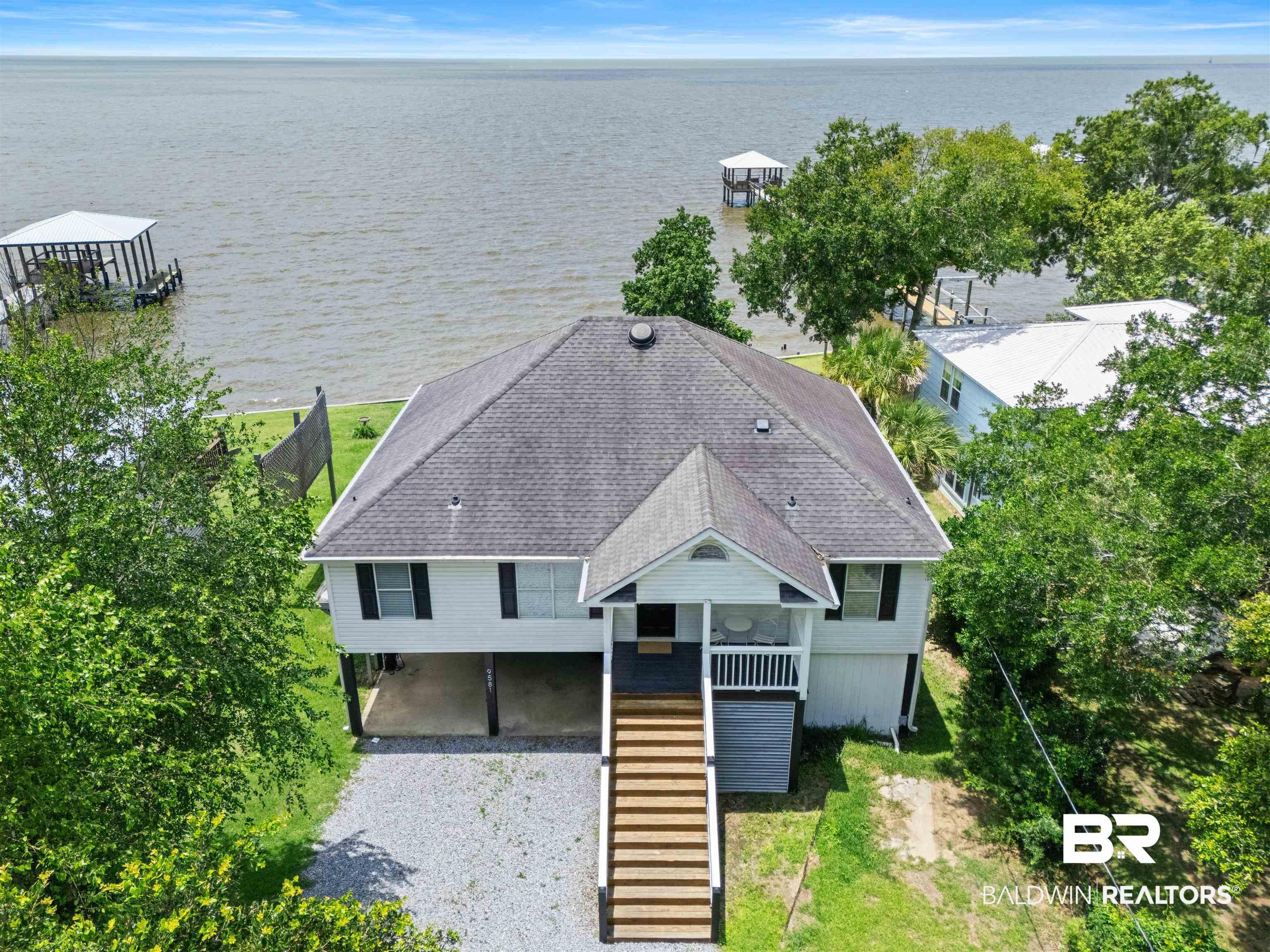 Image 1: Waterfront property featuring an elevated design, a private covered boat dock, and a gravel driveway